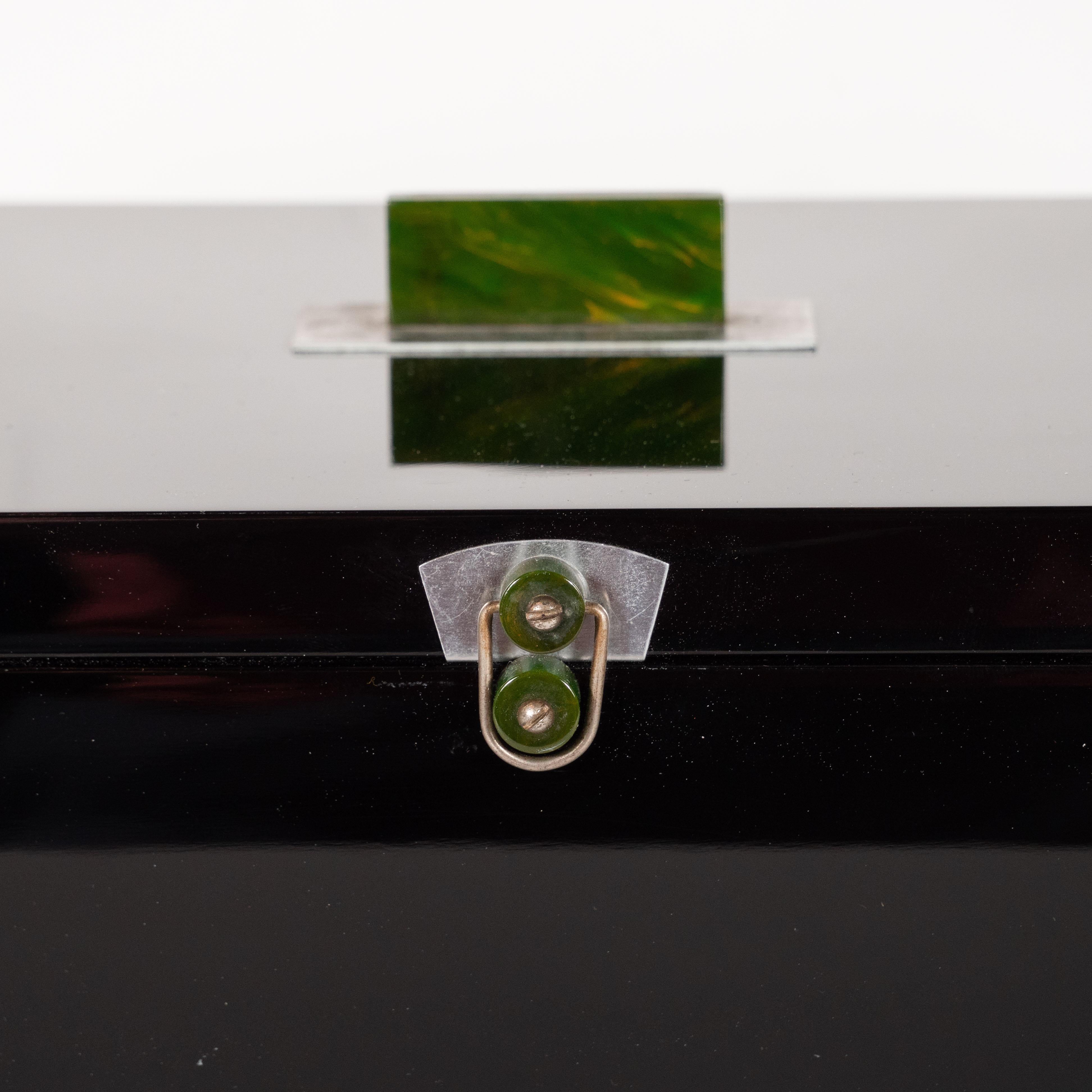 This elegant machine age Art Deco box was crafted in the United States, circa 1935. It features a rectangular body with an elongated geometric brushed aluminium insert in the centre of the top from which a jade bakelite pull of the same shape