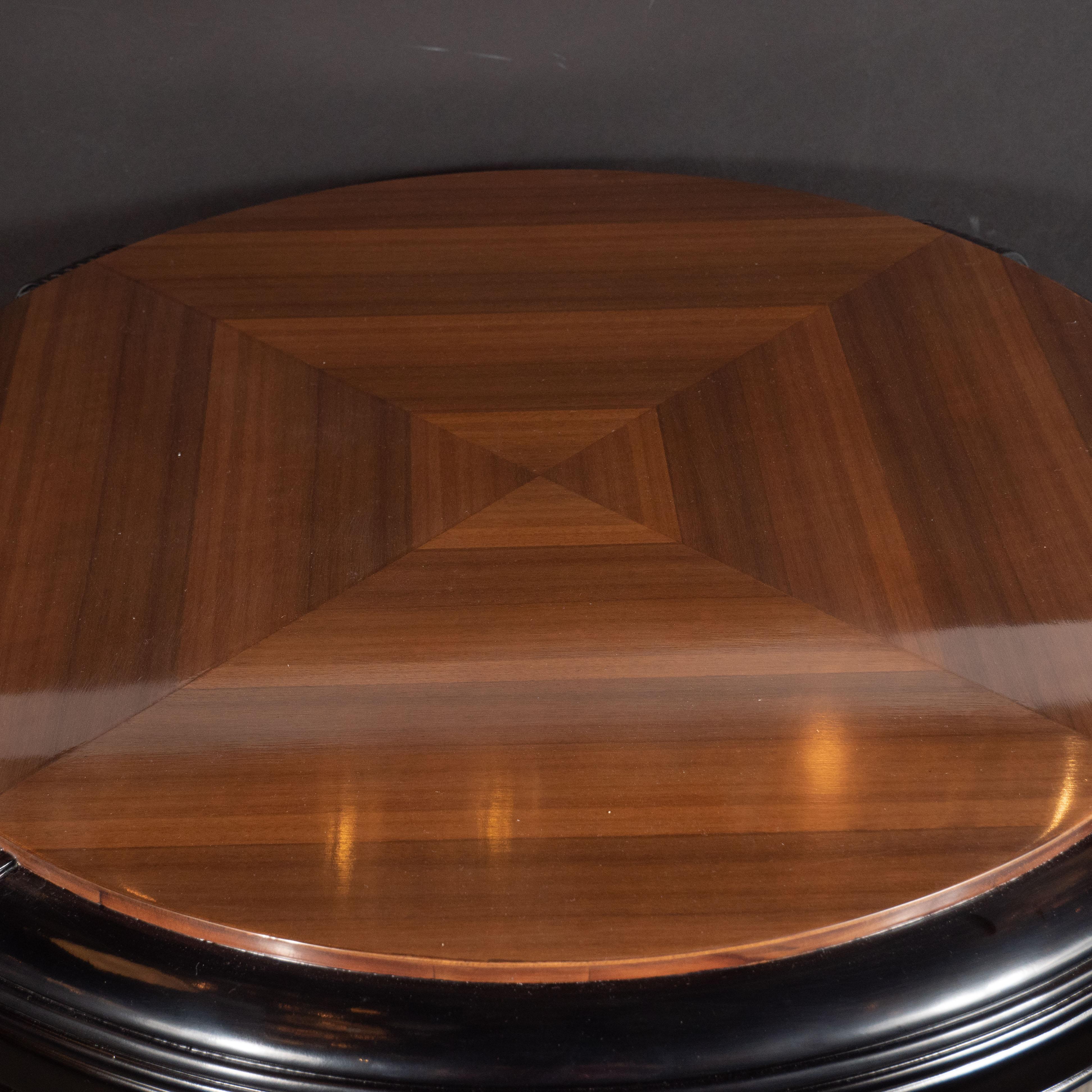This stunning Machine Age streamlined Art Deco table was realized in the United States, circa 1935. It features a walnut top whose grain has been bookmatched to create a series of concentric rhomboid forms. Encircling the top is a reeded apron in