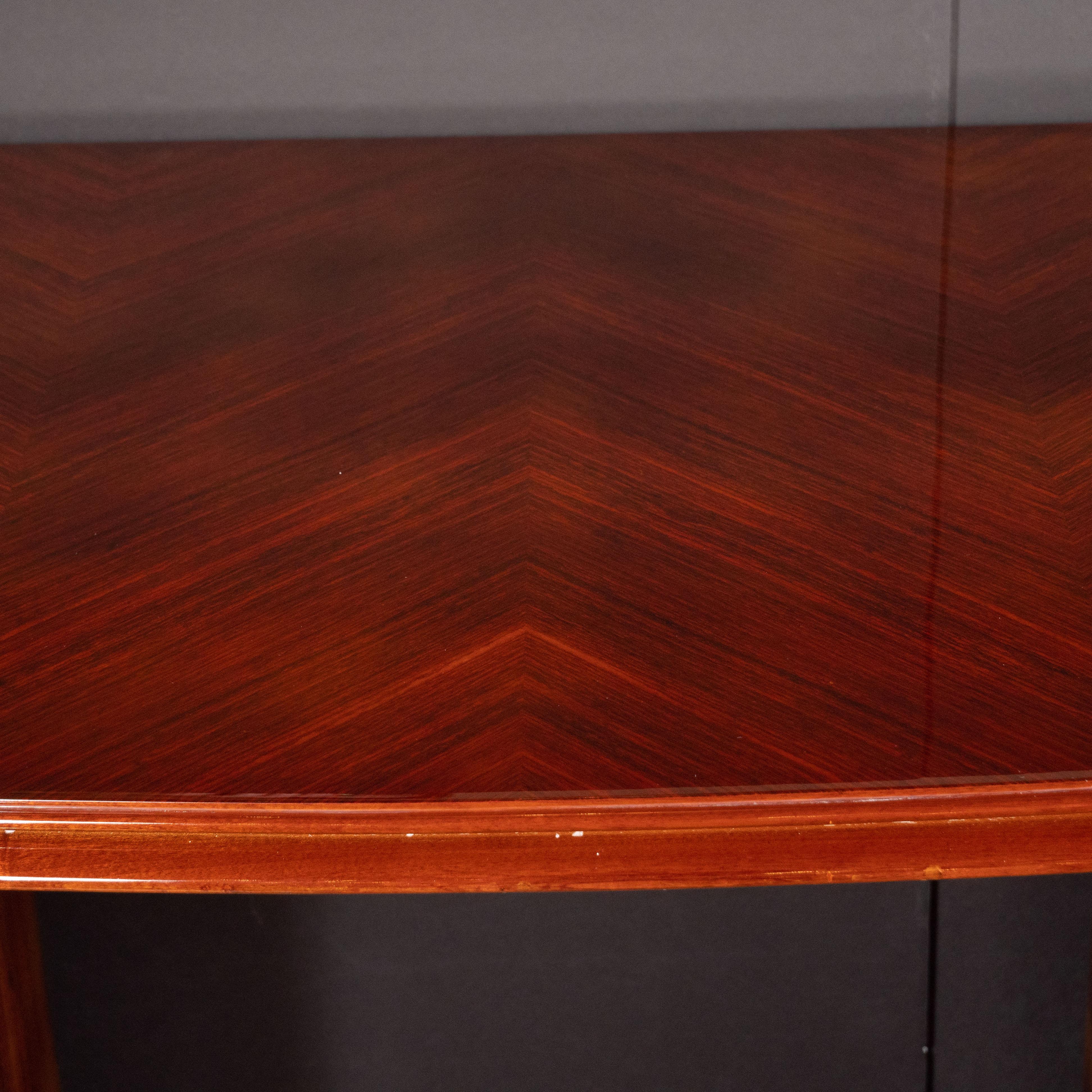 This elegant and refined Art Deco desk was realized in France, circa 1935. It features a gently curved bowfront rosewood top with a skyscraper style stepped perimeter, whose inherent grain has been bookmatched to create chevron patterns throughout.