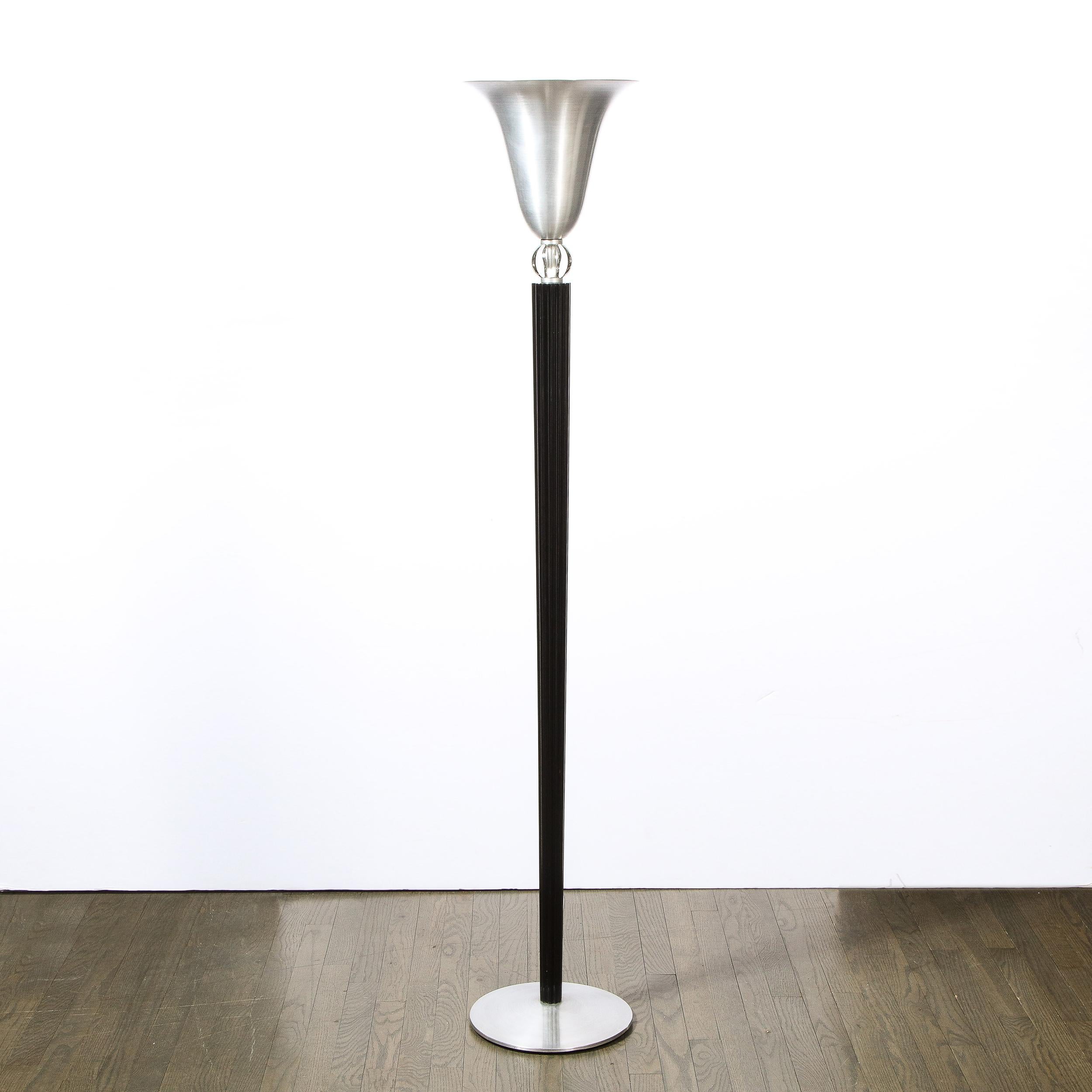 This refined Art Deco Machine Age floor lamp was realized by the legendary designer Russel Wright circa 1935. It offers a brushed aluminum circular base from which a channeled cylindrical black lacquer body ascends, flaring subtly to its apex. The