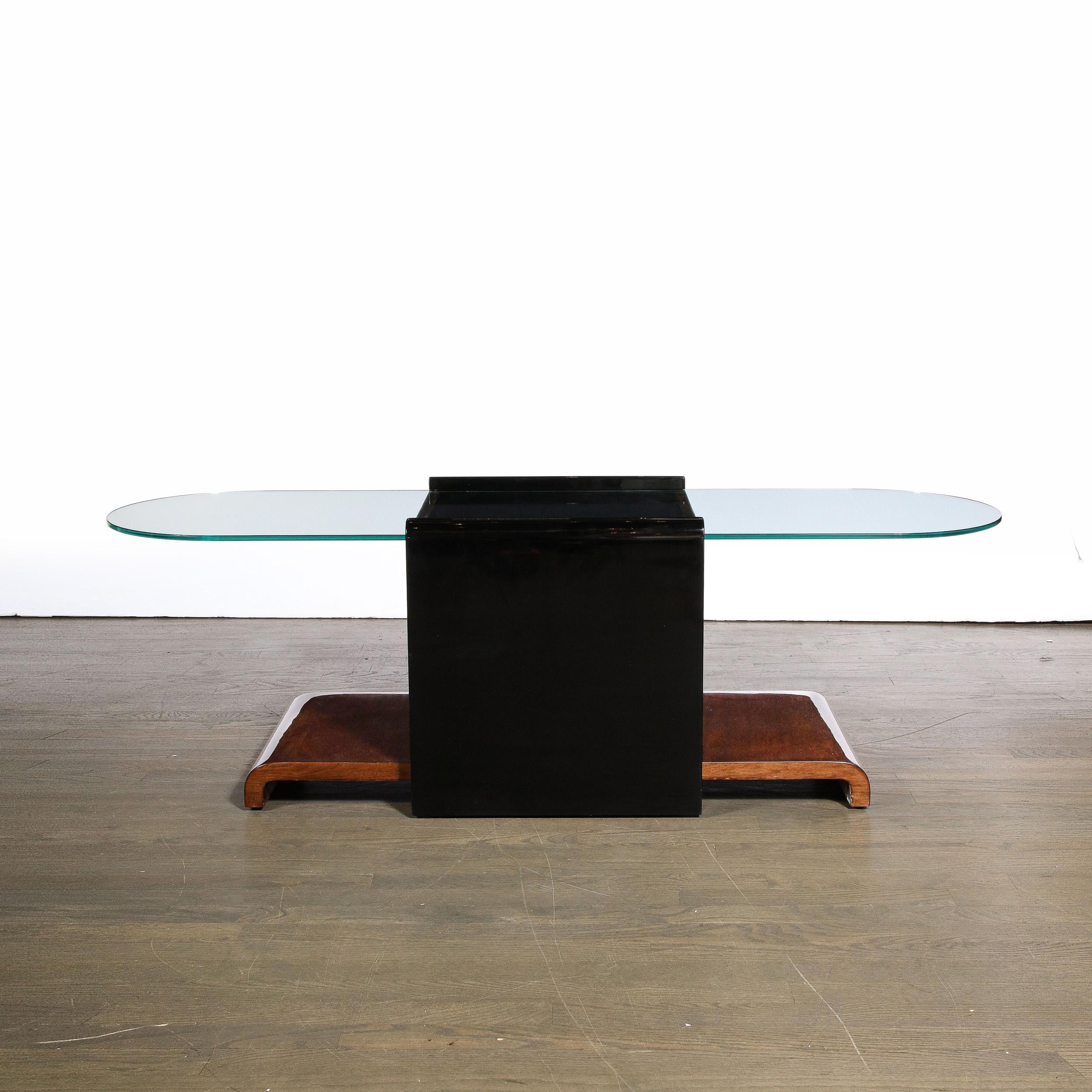 This sleek and highly sophisticated Art Deco Machine Age Bullet Form Cocktail Table in Bookmatched Walnut W/ Black Lacquer Accents & Glass Top originates from the United States, Circa 1935. The table features an elongated oval shaped surface in