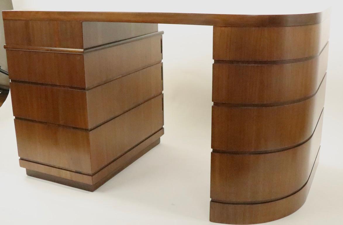 Classic Art Deco Machine Age streamline desk, designed by Donald Deskey. This iconic desk features a dramatic curved side, having speed band veneer trim, with the opposing side having three pull out drawers. The top is an equally dramatic form,
