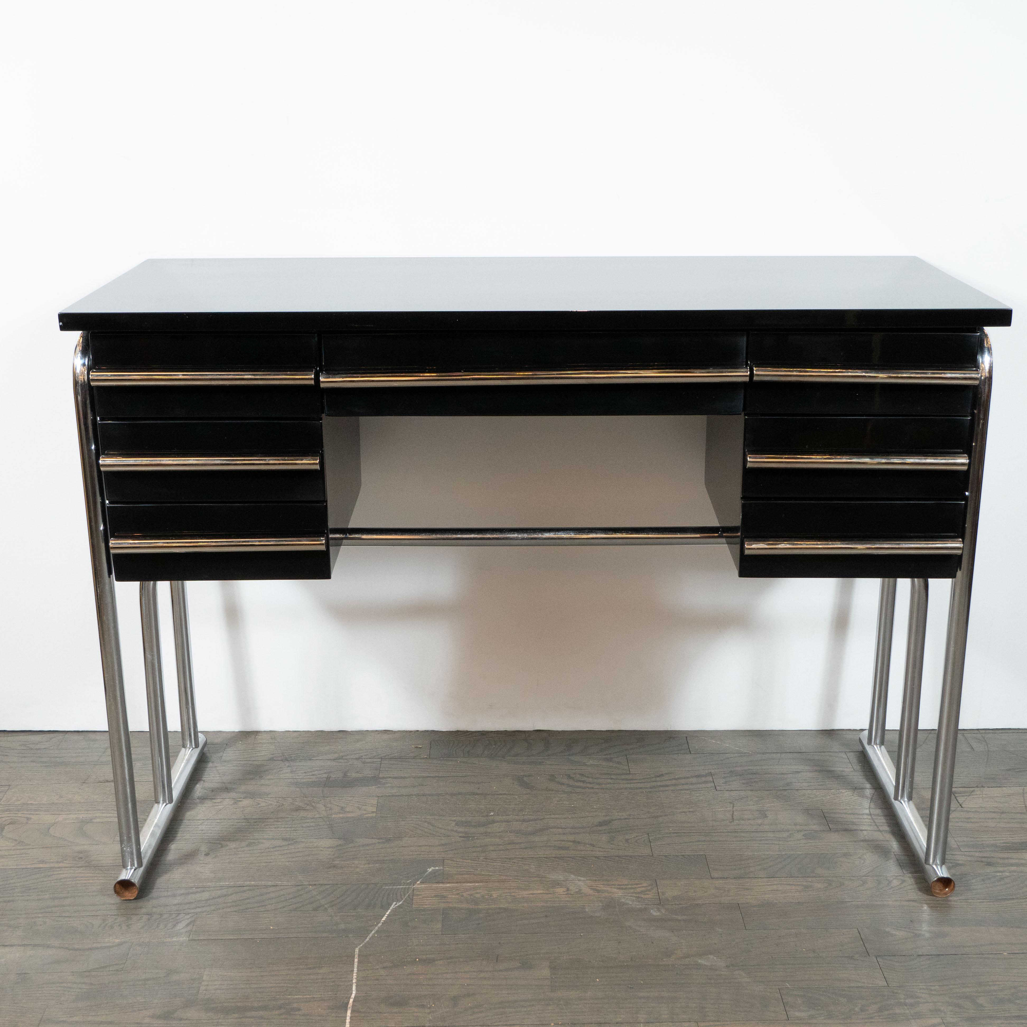 This elegant Art Deco Machine Age desk or vanity in the style of Gilbert Rohde. It features a rectilinear body with a rectangular top, a central drawer and three drawers on each side with cylindrical streamlined chrome pulls- offering a wealth of