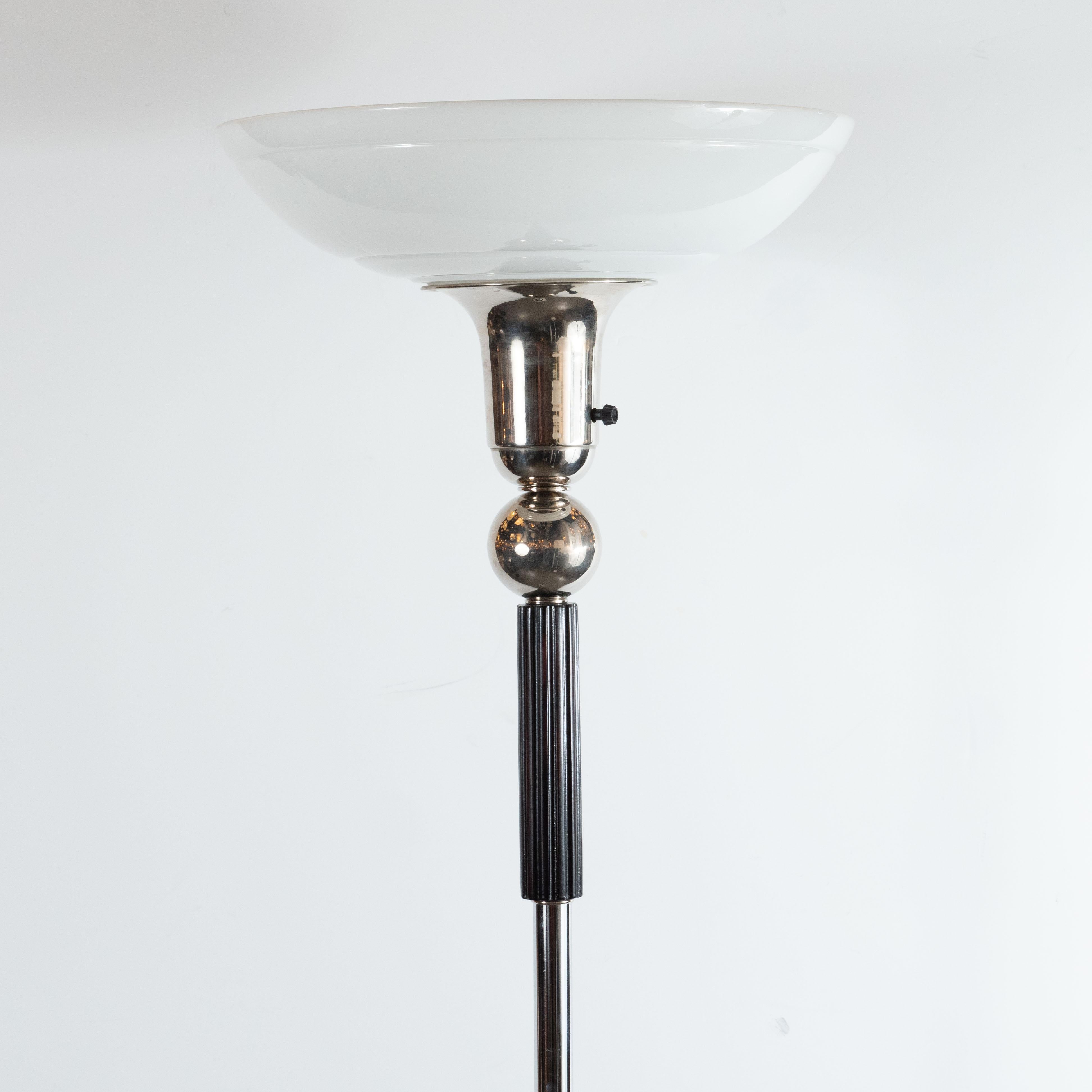 This refined Machine Age Art Deco torchiere was realized in the United States circa 1935. It features a skyscraper style base consisting of alternating tiers of chrome and ebonized walnut. A cylindrical polished chrome stem ascends from the base