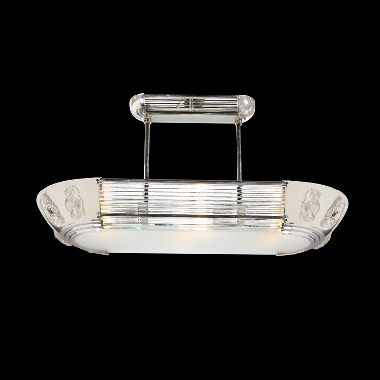 This stunning and rare Art Deco Machine Age chandelier was realised by the legendary atelier of Petitot in France circa 1935. It features a racetrack streamlined form with two curved ends in lustrous polished chrome with stacked translucent glass