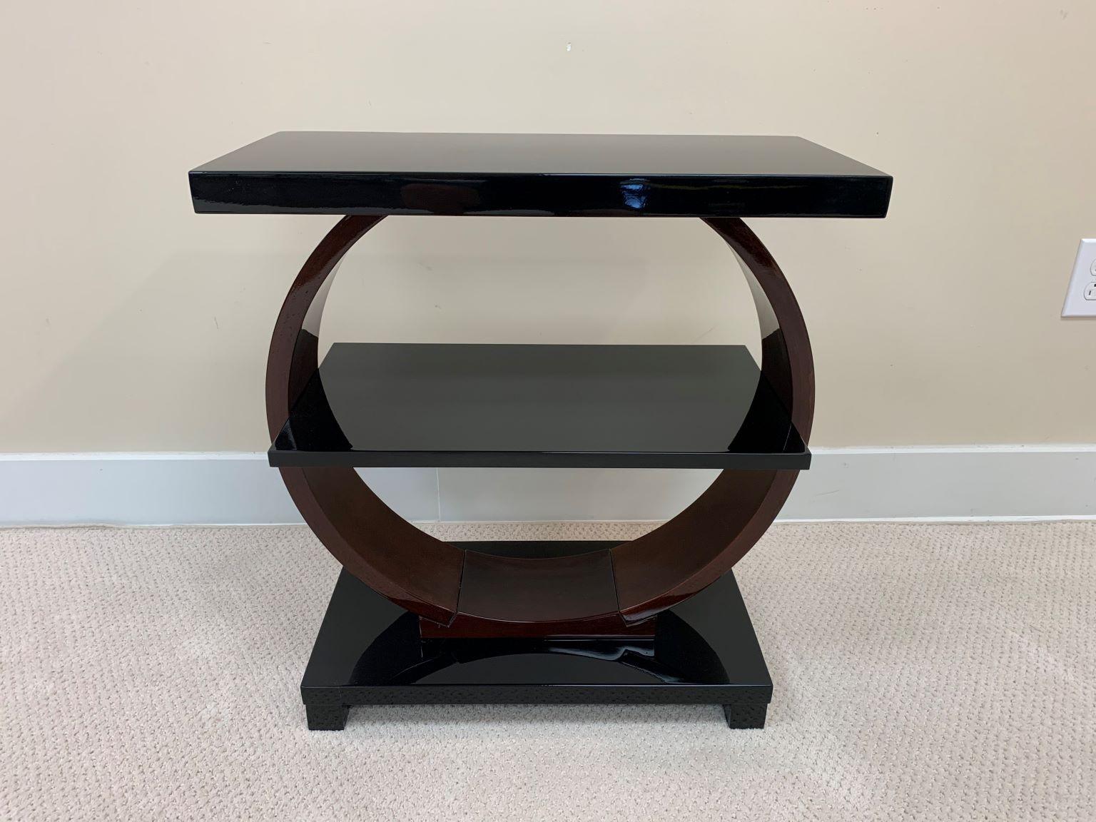 This stunning Art Deco Machine Age table was retailed by The Modernage Furniture Company in the 1930s and 1940s. It features an elegant circular design that supports a rectangular base, shelf and top. This piece is sure to delight collectors of the