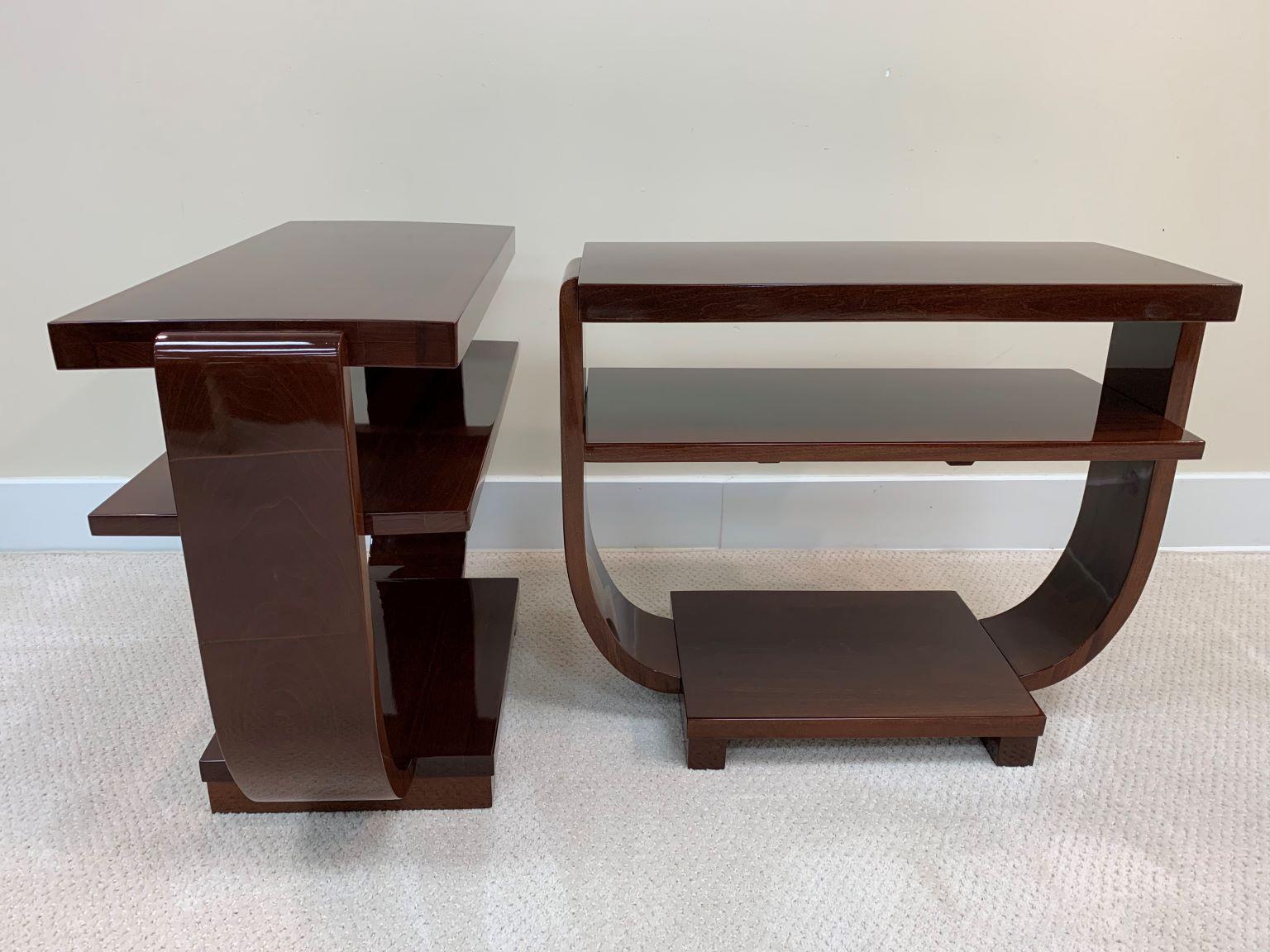 Pair of Art Deco Machine Age end tables made and retail by the Modernage Furniture Company. An elegant design with three shelves supported by a soft curving U. Perfectly restored in a walnut gloss finish. Measures: Height 22 Width 12 Length.