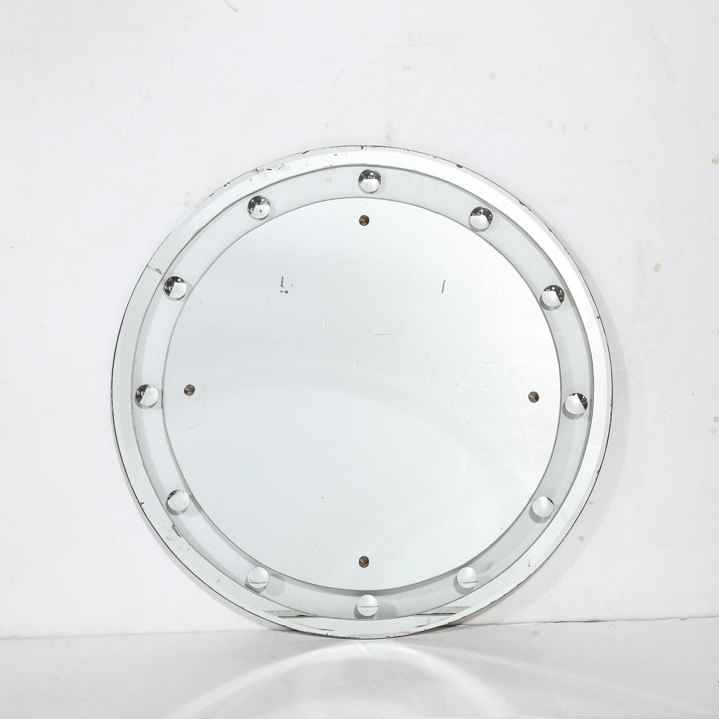 This stunning Art Deco floating edge round mirror was realized in the United States circa 1930. It offers a circular form with two banded layers of mirror circumscribing the perimeter of the central plain round mirror. The innermost band offers