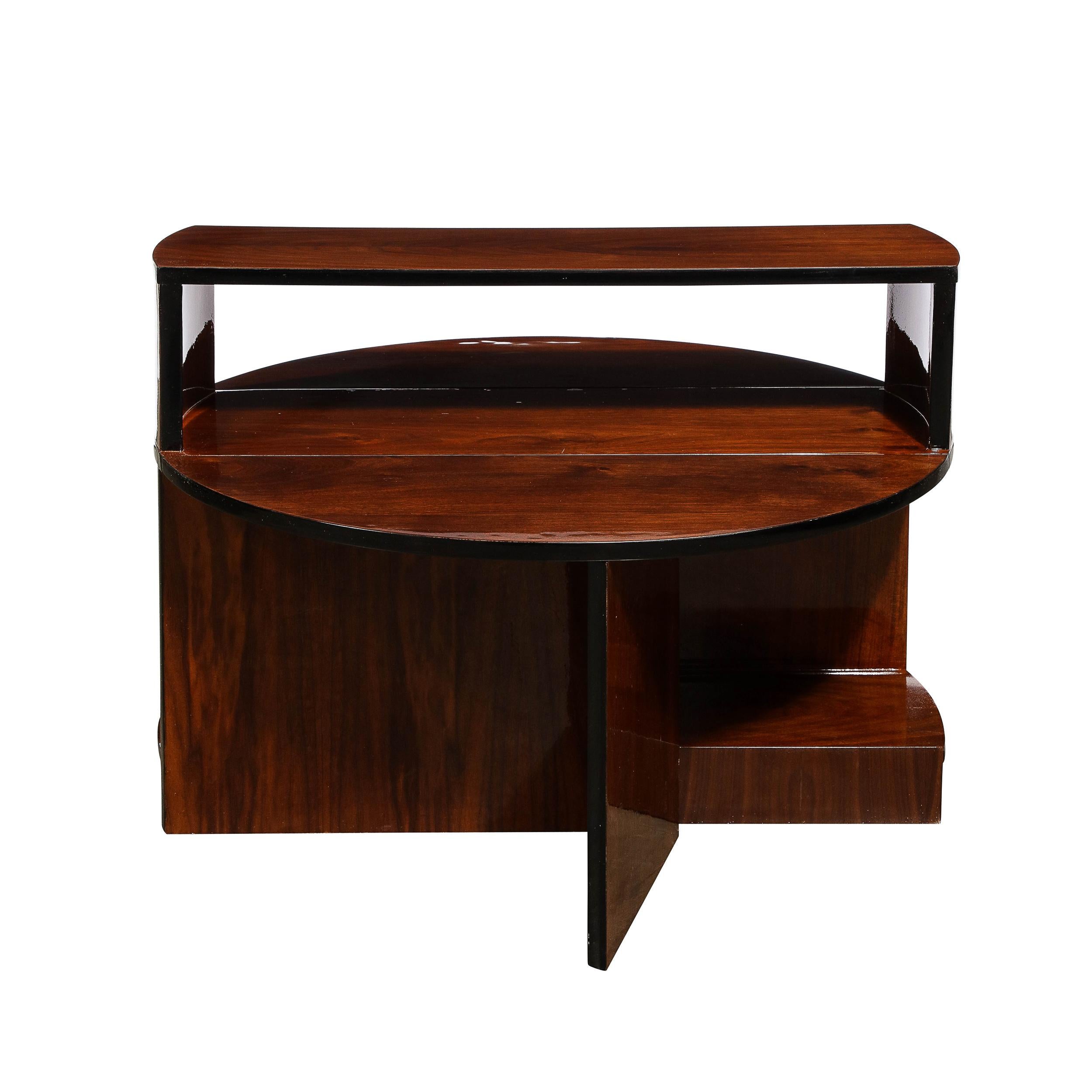This beautiful Art Deco Machine Age cubist folding coffee table was realized in the United States circa 1935. Its graphic silhouette offers a streamlined volumetric rectilinear base in bookmatched walnut with black lacquer edges. When closed, the