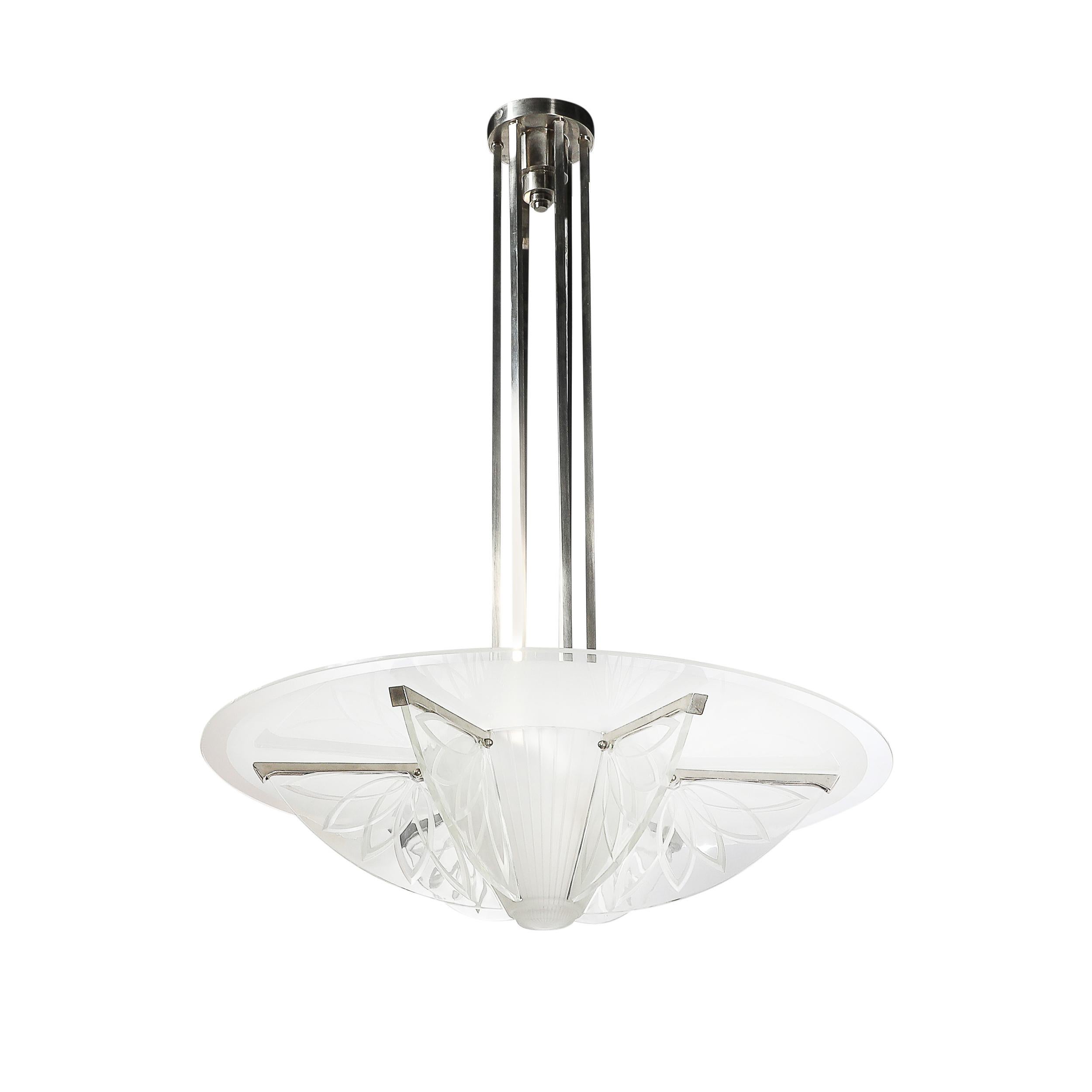 This elegant Art Deco pendant chandelier, designed by Pierre D'Avsen in France circa 1930, is a masterpiece of the Machine Age aesthetic, blending sleek industrial materials with luxurious craftsmanship. With frosted and etched glass elements paired