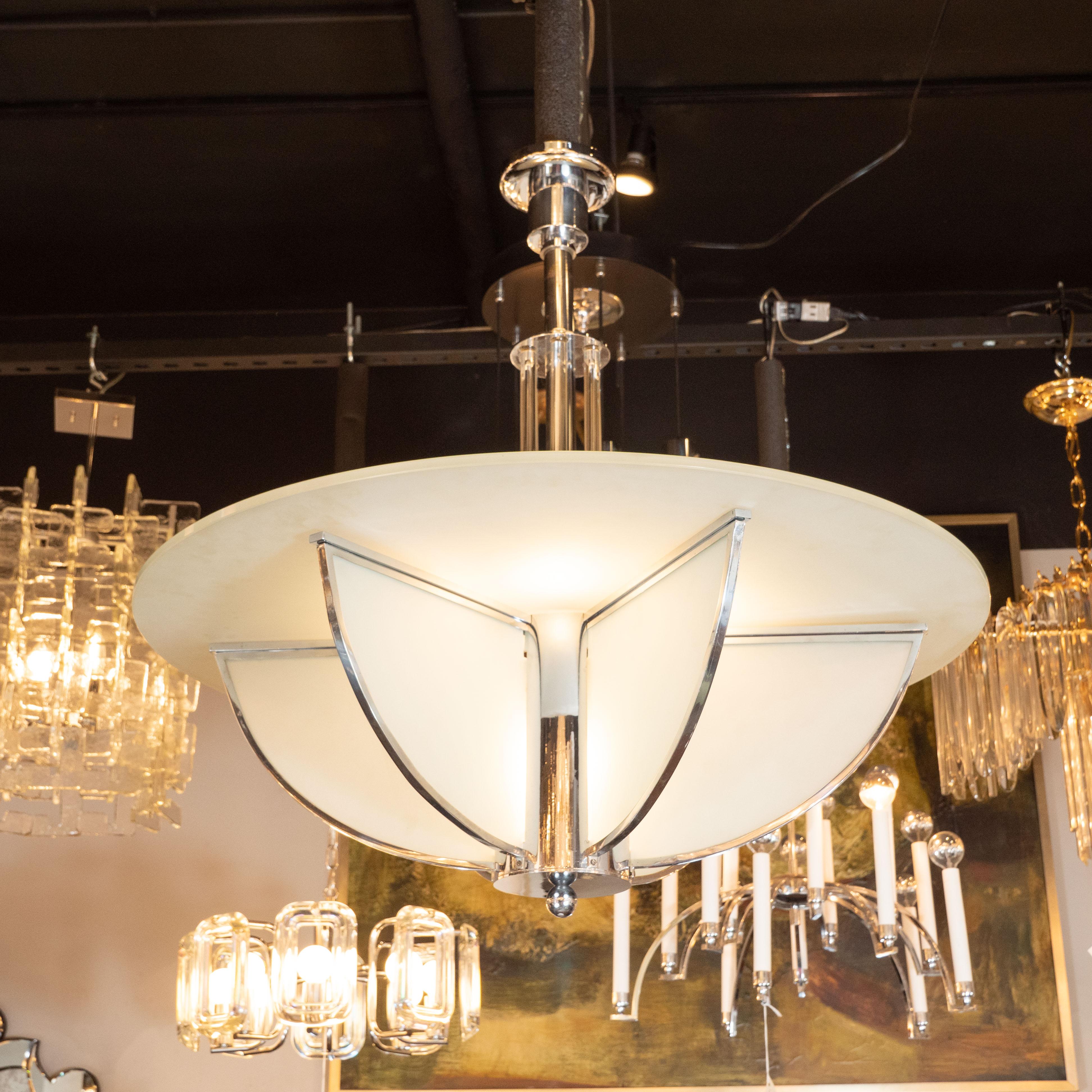 This stunning and graphic Art Deco Machine Age chandelier was realized in France, circa 1935. It features four streamlined fin forms in frosted glass wrapped with chrome that affix to a central cylindrical chrome support capped at its base with an