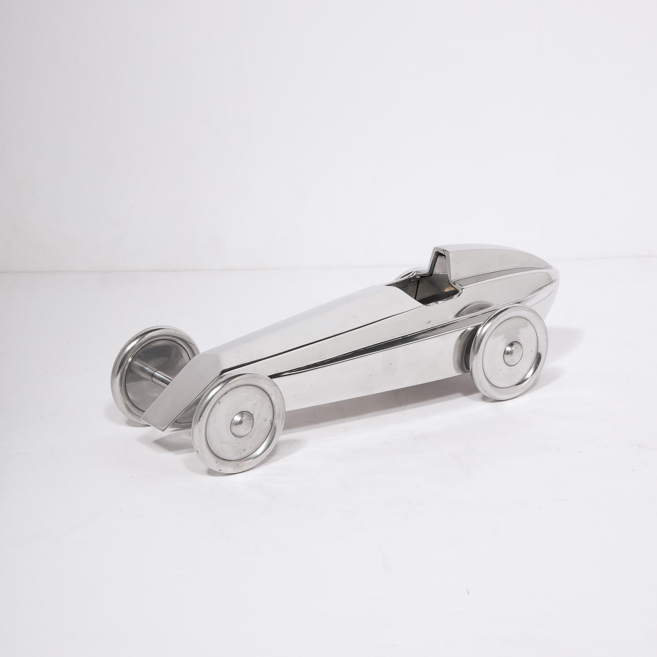 This stunning Art Deco Machine Age race car sculpture was realized in the United States circa 1935. It features a highly stylized race car- reduced to its most elemental aspects- showcasing the modernism of the form. The car sits on four circular