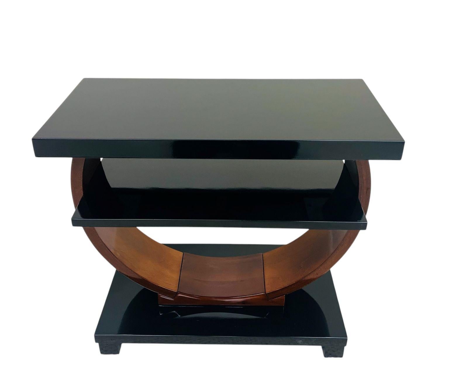     This stunning Art Deco Machine Age table was retailed by The Modernage Furniture Company in the 1930’s and 1940’s. It features an elegant circular design that supports a rectangular base, shelf and top. This piece is sure to delight collectors