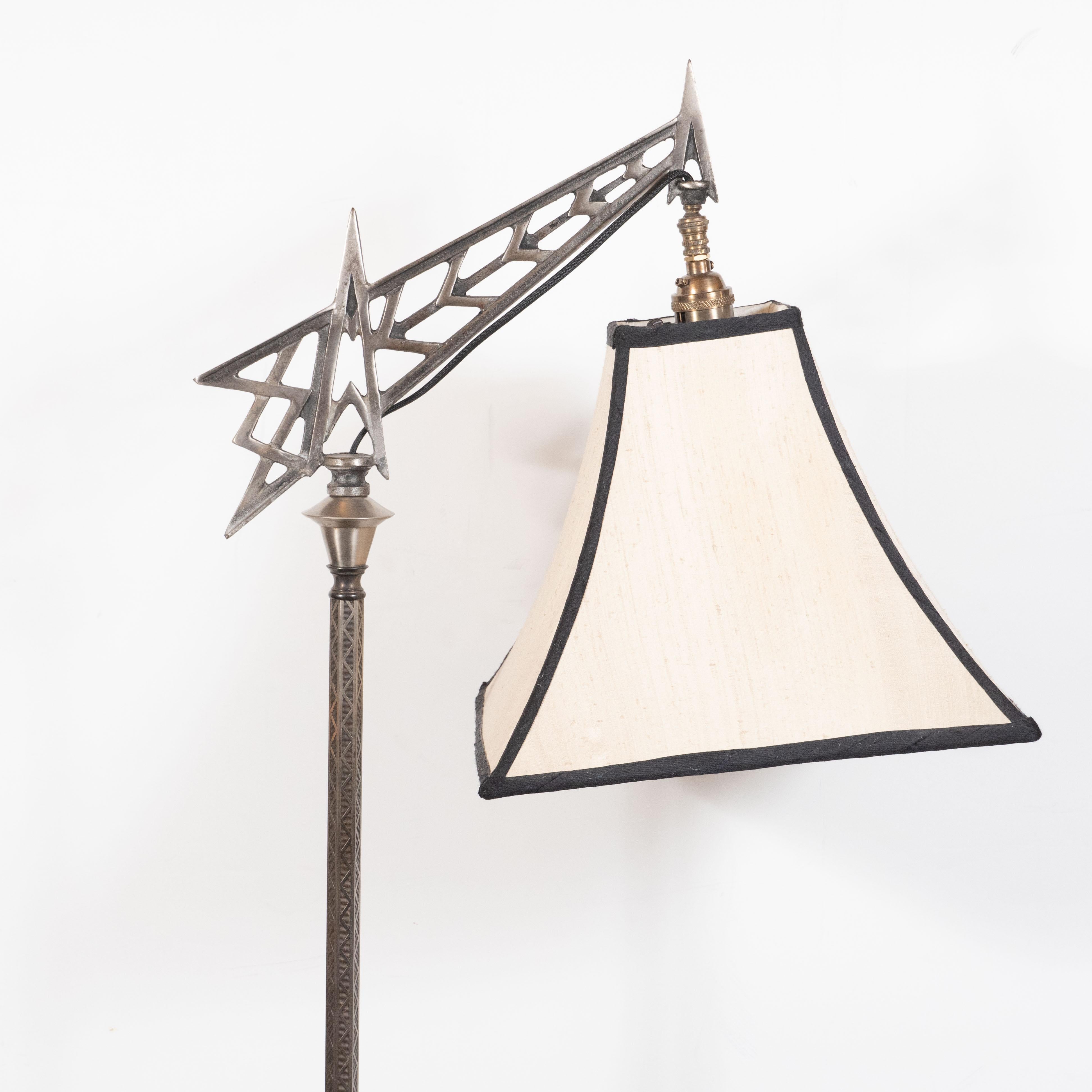 This refined and sculptural Art Deco Machine Age floor lamp was realized in the United States, circa 1930. It features a square base with geometric detailing at each corner that ascends into a skyscraper style embellishment consisting of tiered