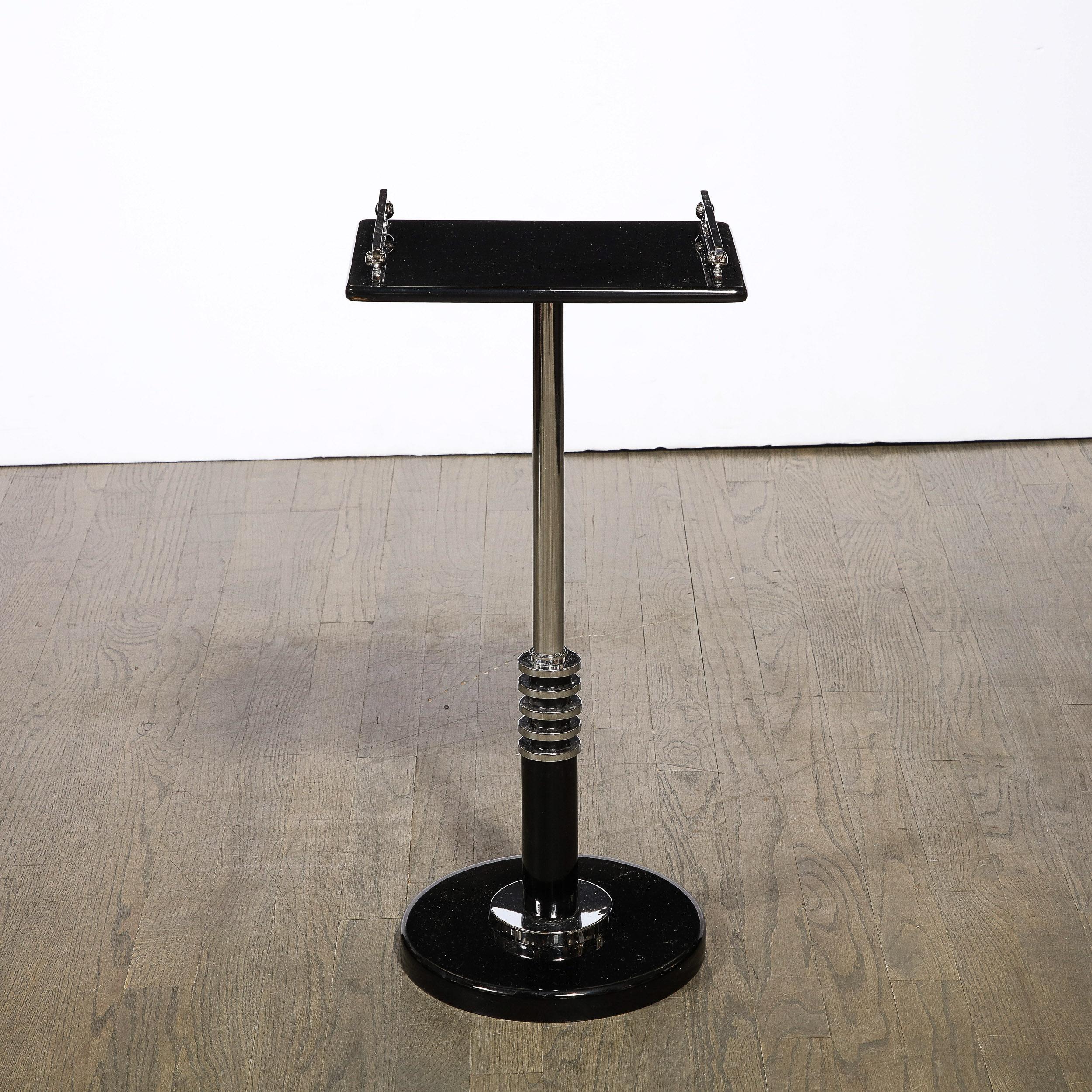 This stunning and graphic Art Deco Machine age drinks table was realized in the United States circa 1935. It features a skyscraper style tiered base consisting of a lustrous chrome circular form sitting on a black lacquer base of the same shape. A