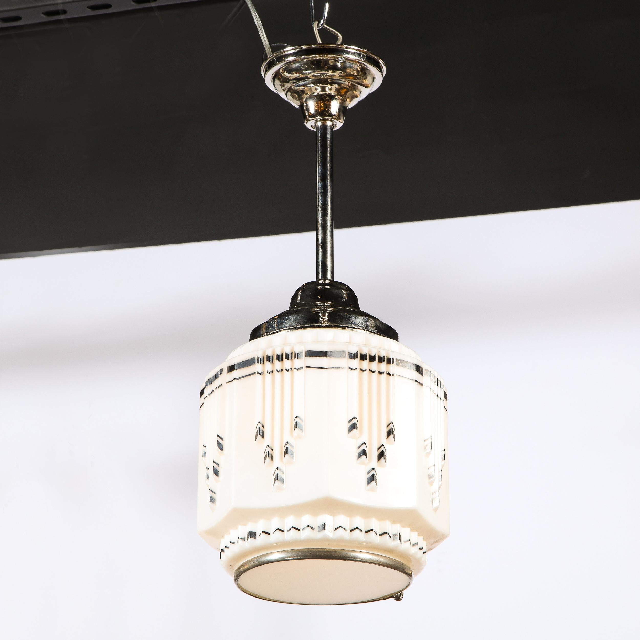 This refined and graphic Art Deco Machine Age pendant was realized in the United States circa 1935. It features a cylindrical body faceted concave sides that extend outwards in the center channeled staggered skyscraper style black etched detailing