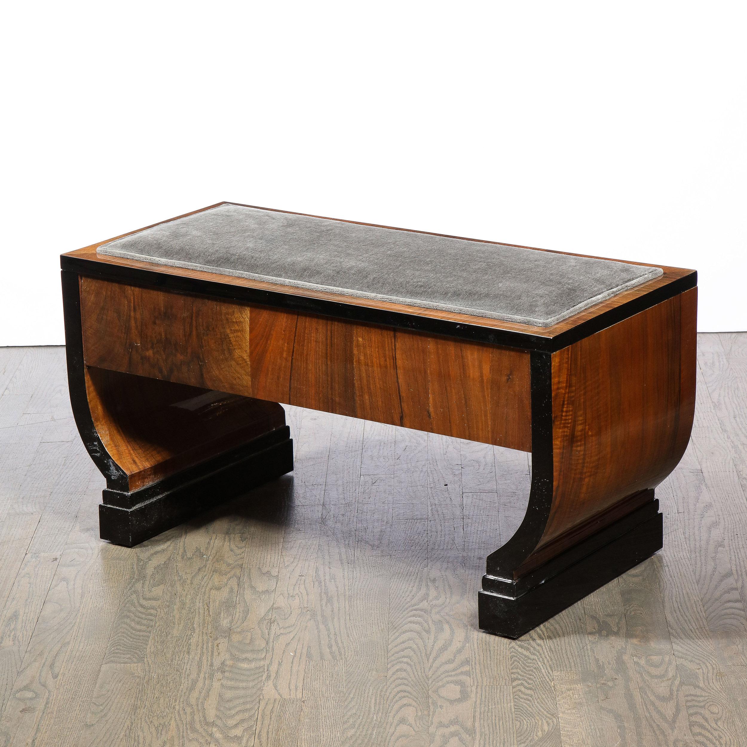 This stunning Art Deco Machine Age bench was realized in the United States circa 1935. It features skyscraper style black lacquer feet, streamlined side and a volumetric rectangular seat with lacquer accents on the edges. The seat has been newly