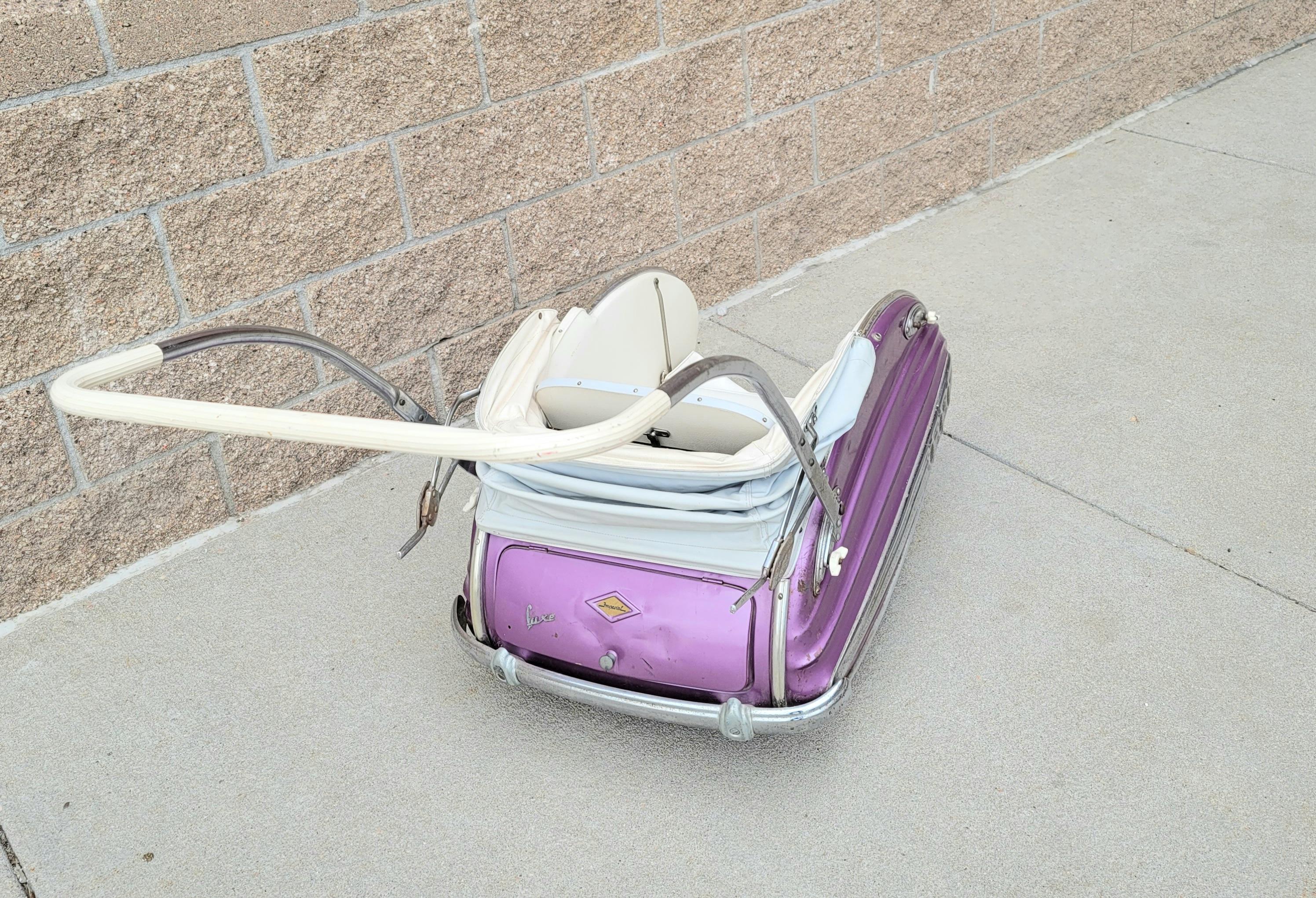 Fantastic early Machine Age Art Deco streamline pram stroller. Ca. 1940s. The body is magenta with chrome sides and chrome bumpers. The hood and interior are plastic and there is a rain cover that is plastic and is detachable. The wheels i believe