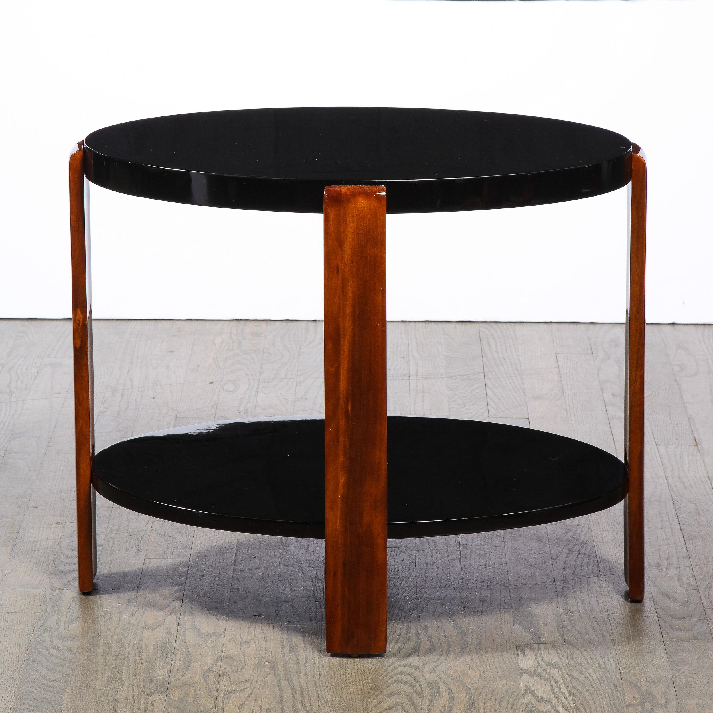 This stunning Art Deco Machine Age table was realized in the United States circa 1935. It offers two ovoid tiers connected via streamlined supports in bookmatched walnut. With its iconically Art Deco sensiblity (and materials) this piece is sure to