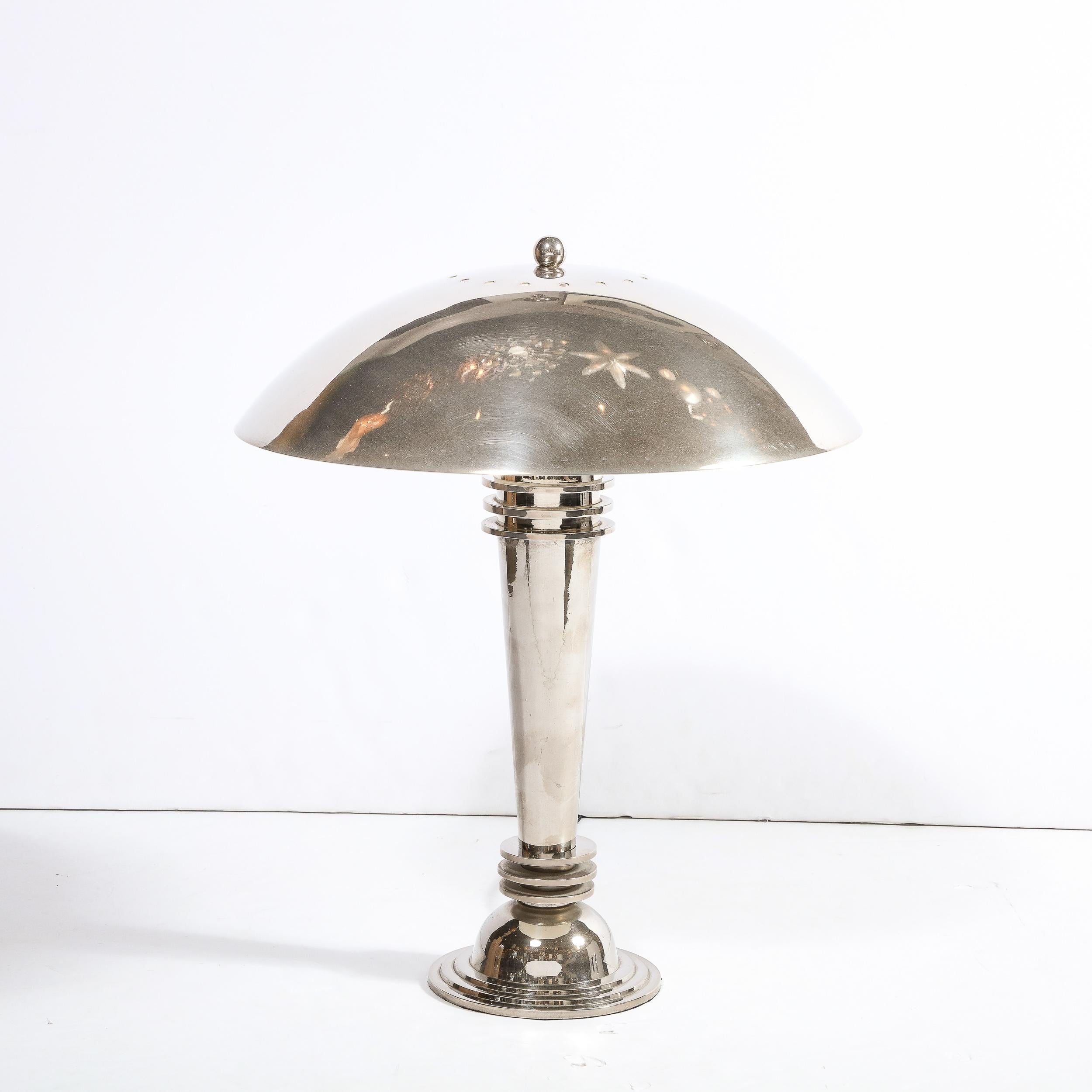 This stunning Art Deco Machine Age table lamp was realized in the United States circa 1935. It features a skyscraper style convex domed base with three concentric bands in relief in lustrous polished chrome. The elongated conical body of the lamp