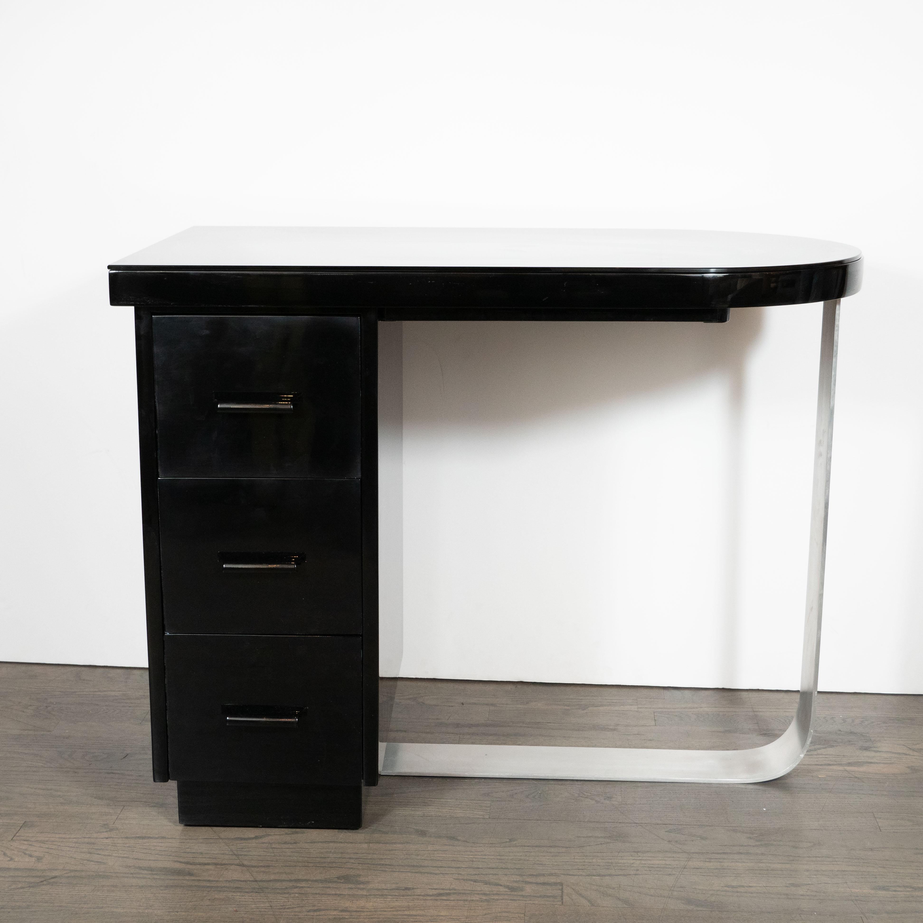This elegant Machine Age Art Deco desk was realized in the United States, circa 1935. It features a streamlined black lacquer top (fitted with a layer of protective black glass) suggesting a stylized bullet- a form that manifests the period's