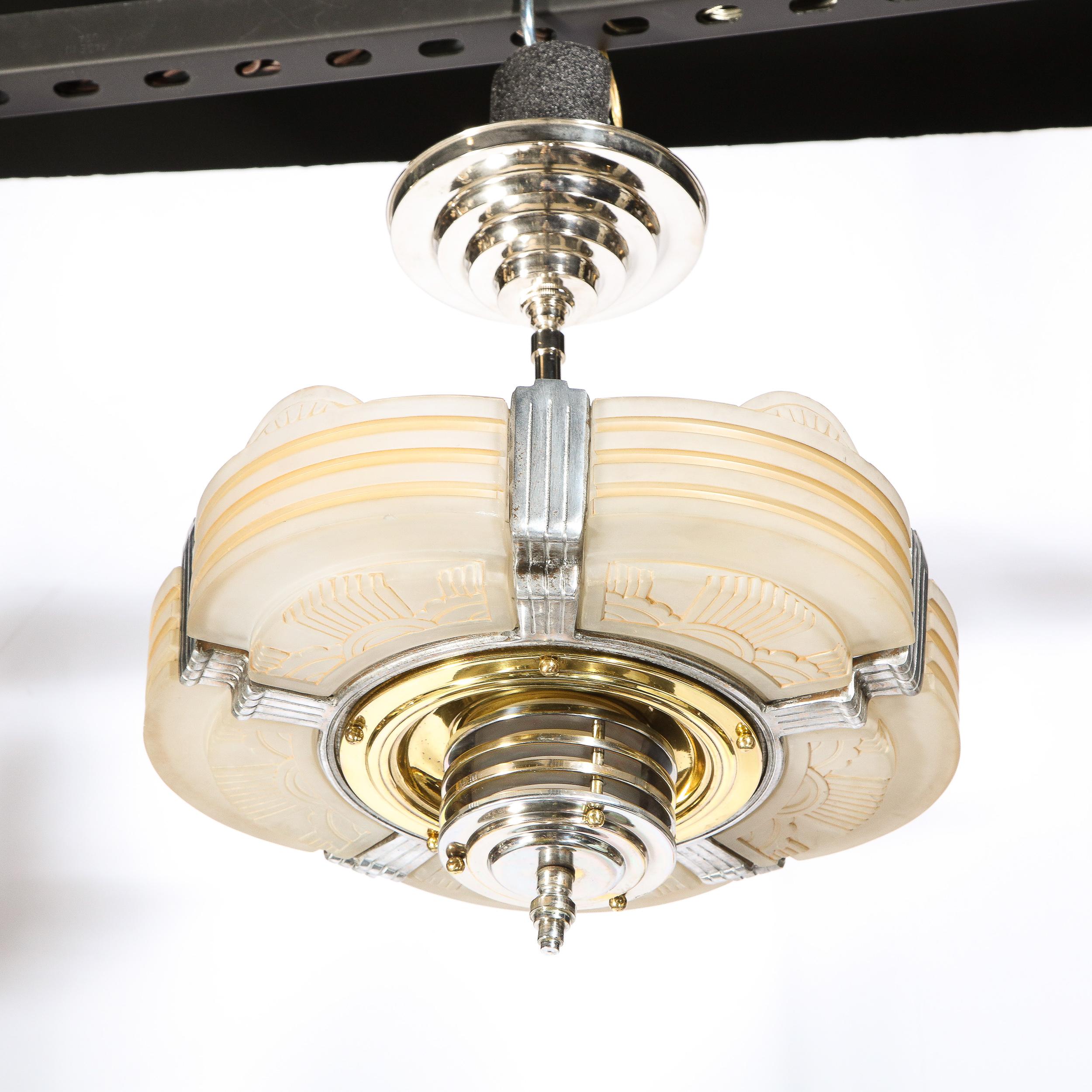 This elegant Art Deco Machine Age chandelier was realized in the United States circa 1935. It features five rose hued glass panels with channeled sides and etched sun/cloud motifs on the bottom of each. The glass secured with streamlined channeled