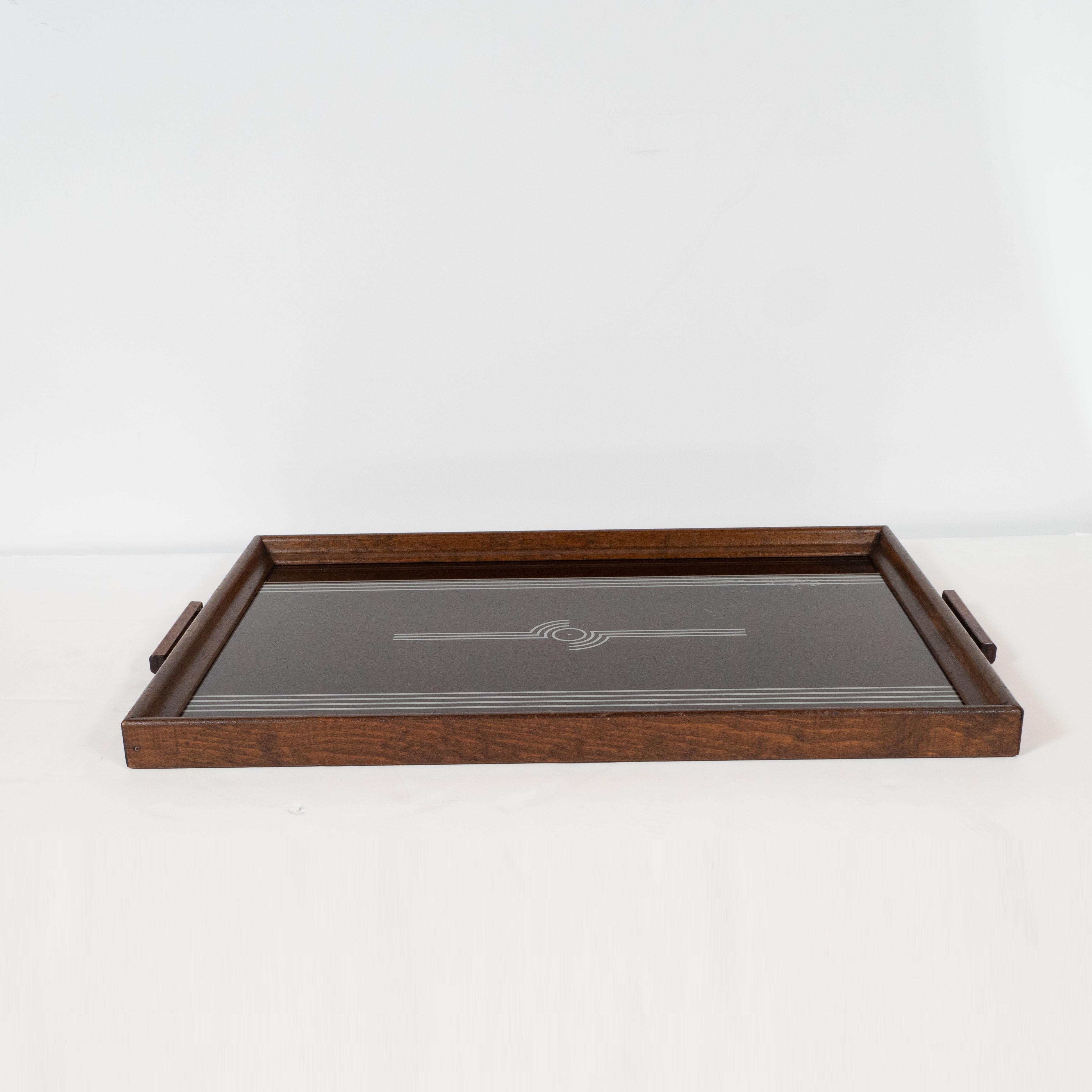 This elegant tray features glass hand painted geometric streamlined designs in sterling silver over an ebonized walnut body. The perimeter body has been executed in hand rubbed walnut with pentagonal handles of the same material. This is a beautiful
