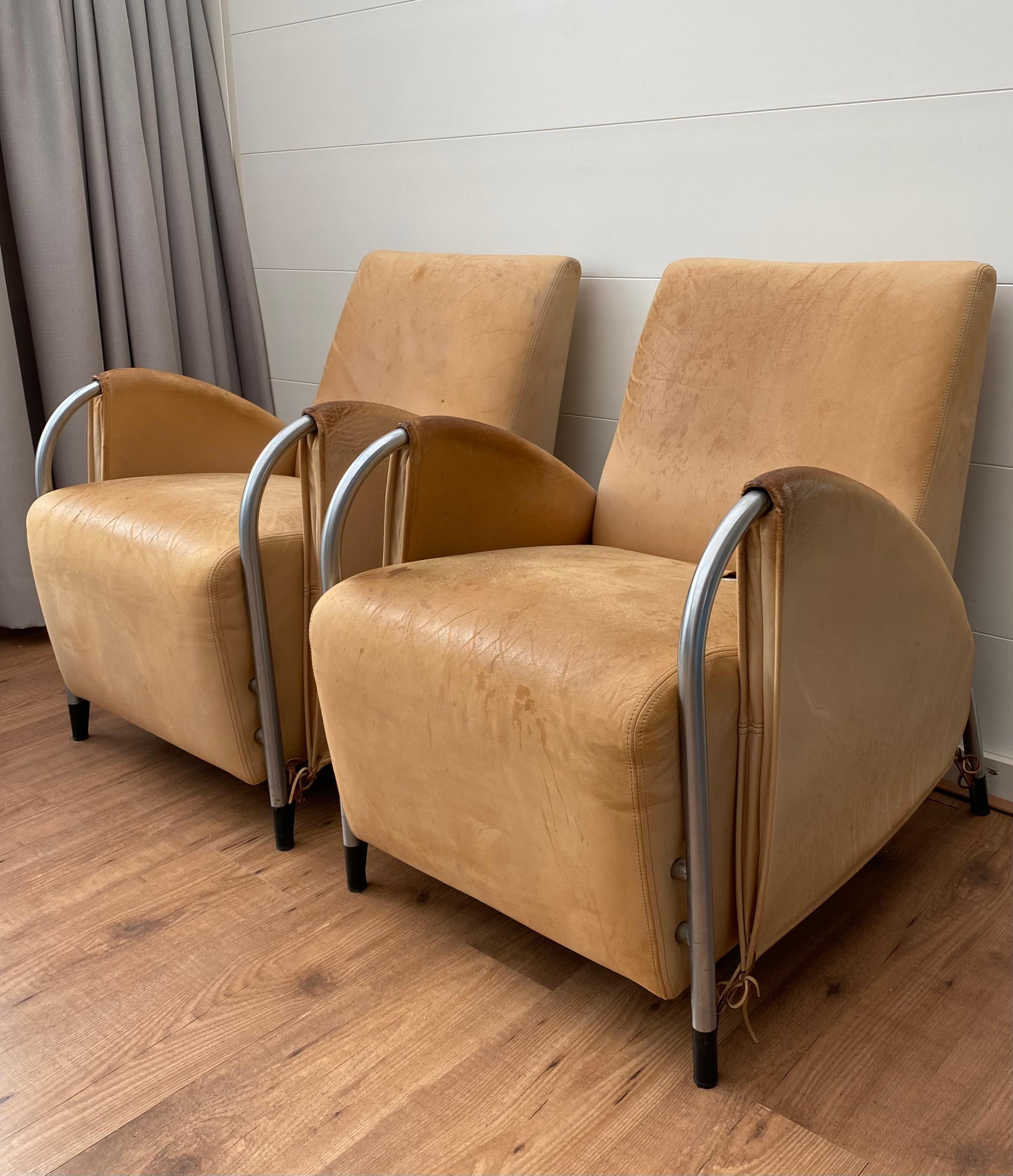 Pair of rare and highly desirable armchairs designed by Jan des Bouvrie for Gelderland. The chairs feature a tubular base with black accents and are upholstered in thick leather. Both chairs need to be reupholstered while the leather shows stains,