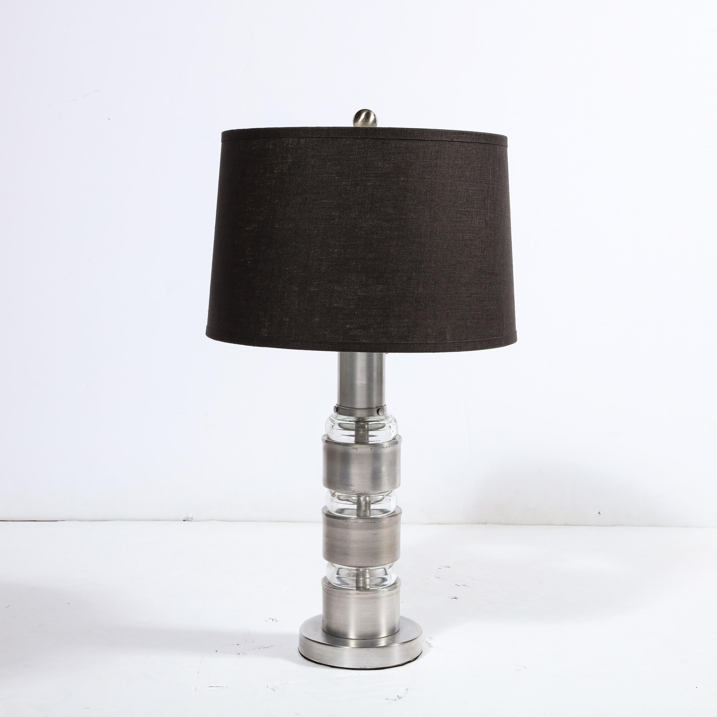 This refined pair of Art Deco Machine Age table lamps were realized by the fabled industrial Designer Russell Wright in the United States circa 1935. They feature circular volumetric bases in brushed aluminum from which the body of each lamp
