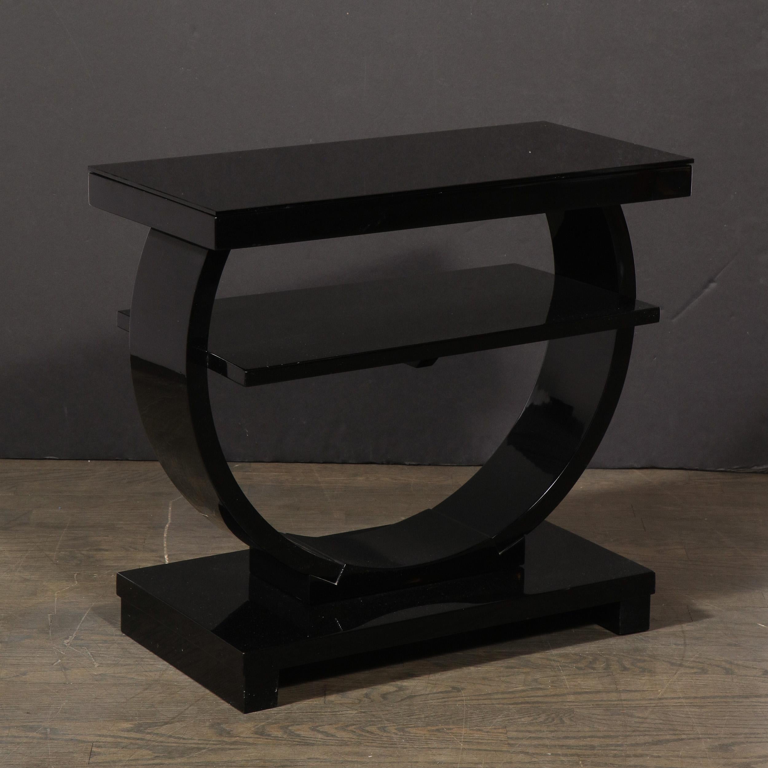 This fine and graphic Art Deco Machine Age side table was realized in the United States, circa 1935. It features a geometric open demilune form pierced through the center with a rectangular tier. The top of the table is another rectangular form