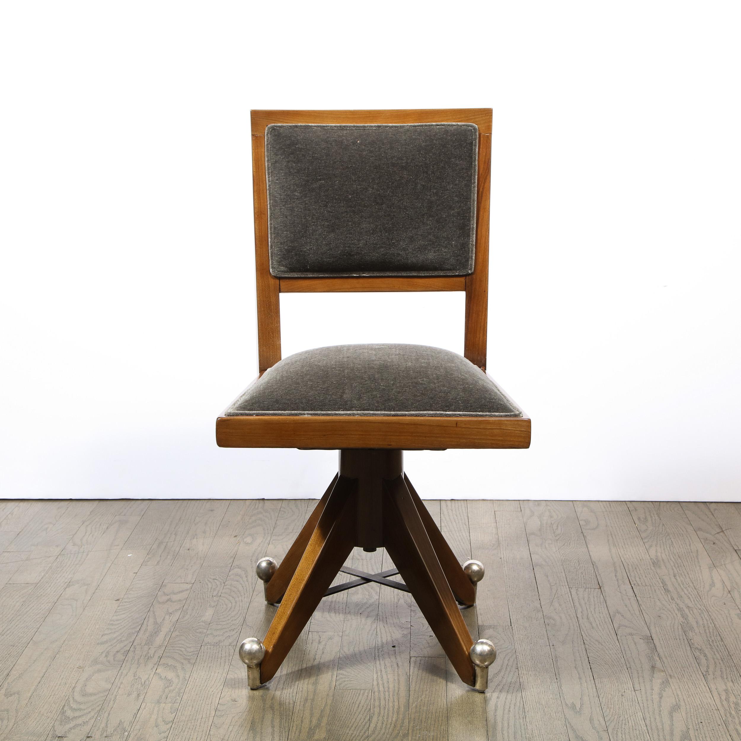 This stunning Art Deco Machine Age swiveling side chair was realized in France, circa 1935. It features a hand rubbed walnut frame with a slate mohair back and seat. The splayed walnut feet are connected via nickeled x form fittings. Additionally,