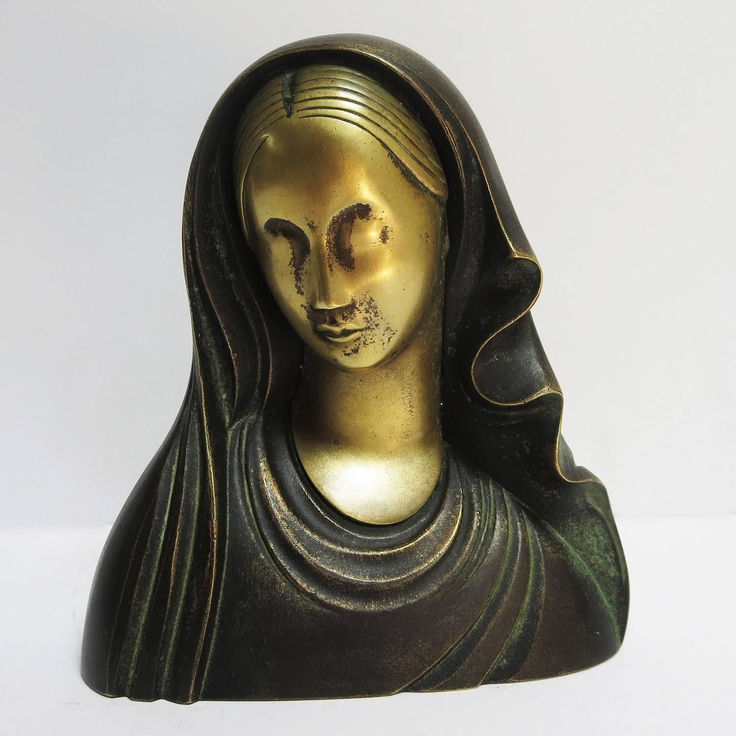 This lovely sculpture in created in two parts. The face is a brass tone, while the clothing is a darker patina finish. The base is wooden, and marked 