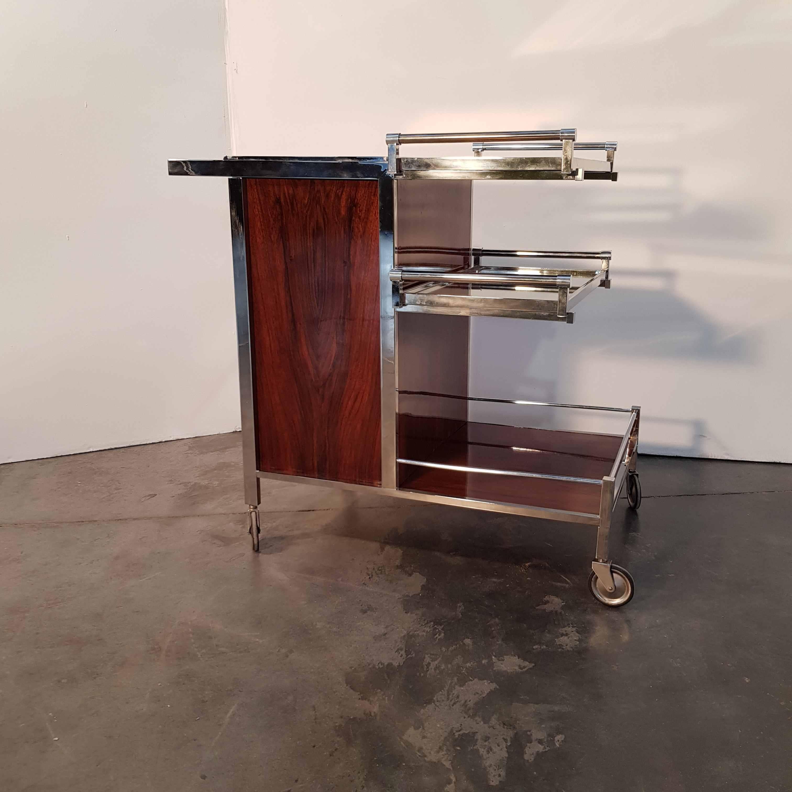 Unique bar cart, with mahogany, nickel-plated metal, mirrors and glass. Two removable trays, one top compartment for ice, one compartment with 2 doors for bottles and glasses with glass holders. Tray handles and pushbar in solid glass. 1930s,