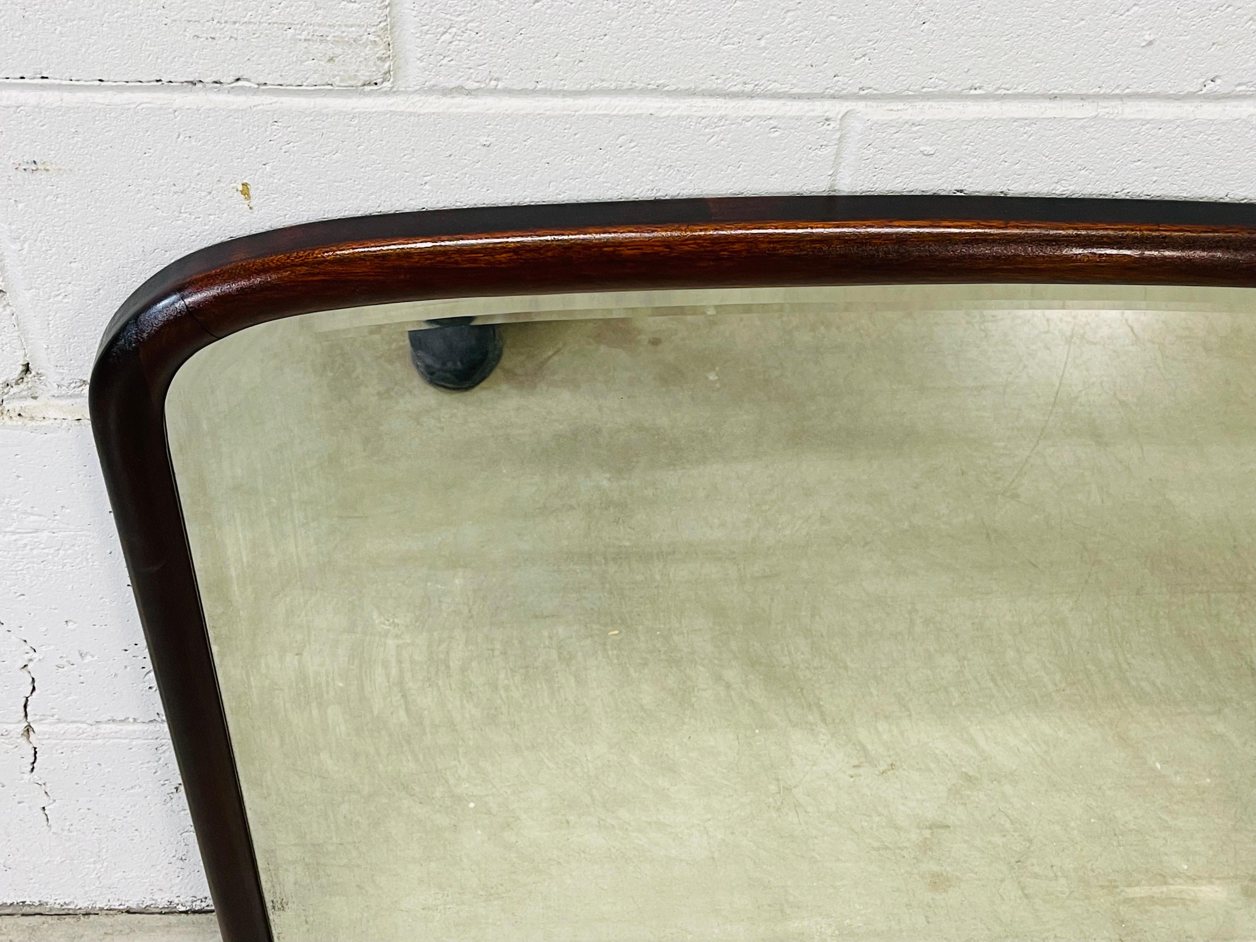 Vintage Art Deco mahogny rounded top wall mirror with a beveled edge. The wood frame is newly refinished. The mirror has a light haze from age. No marks and no hardware is included.