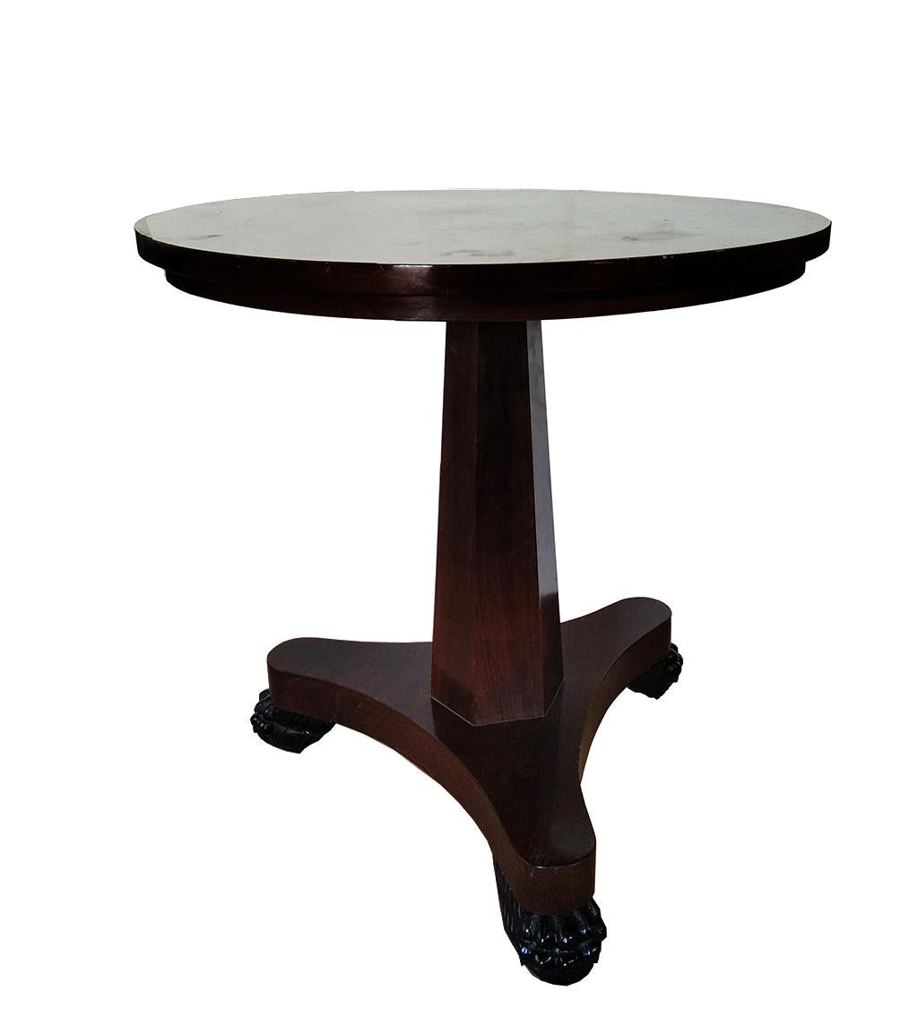  Eleganter und robuster Tisch mit sehr klaren linearen Formen. Der Sockel, auf dem er steht, ist nicht rund, sondern hat eine optagonale Säulenform.

Er ist aus Mahagoniholz gefertigt und die Beine enden in Krallen aus Ebenholz.
Es ist ein ganz