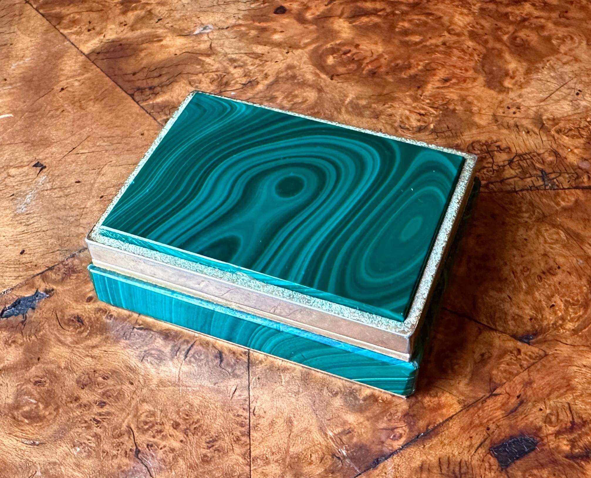 Here is an elegant Antique Art Deco Malachite and Brass lidded jewelry or pill or trinket box. This piece features vibrant, wonderful quality green malachite with stunning graining. 
The malachite is fitted on the top as well as all four sides of