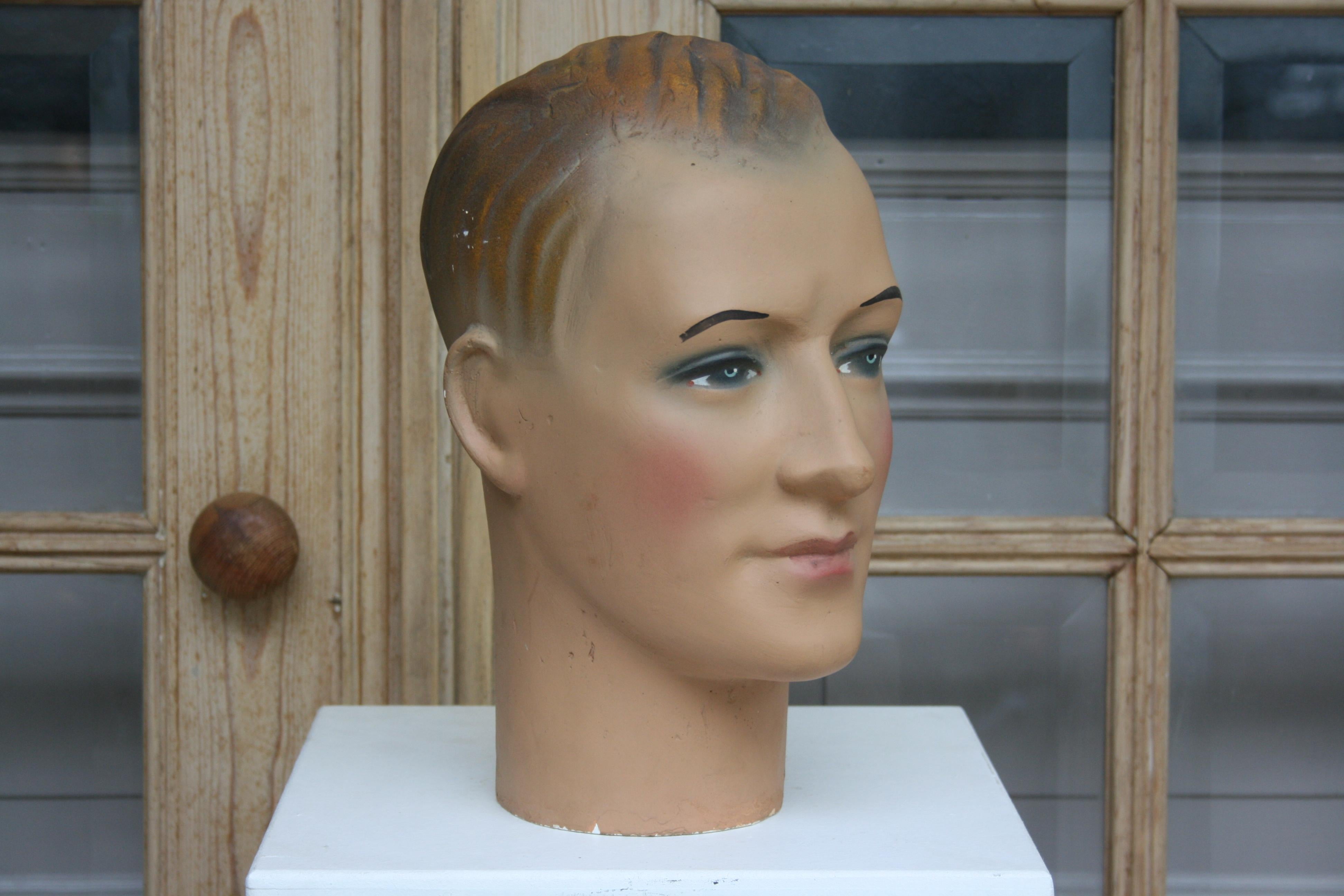 The mannequin head of a young man dates back to the 1930s of the 20th century and is made of plaster. It is painted polychrome. The man is wearing makeup and has painted eyes.

Dimensions:
31 cm high / 12.2 inch high,
17 cm wide / 6.69 inch