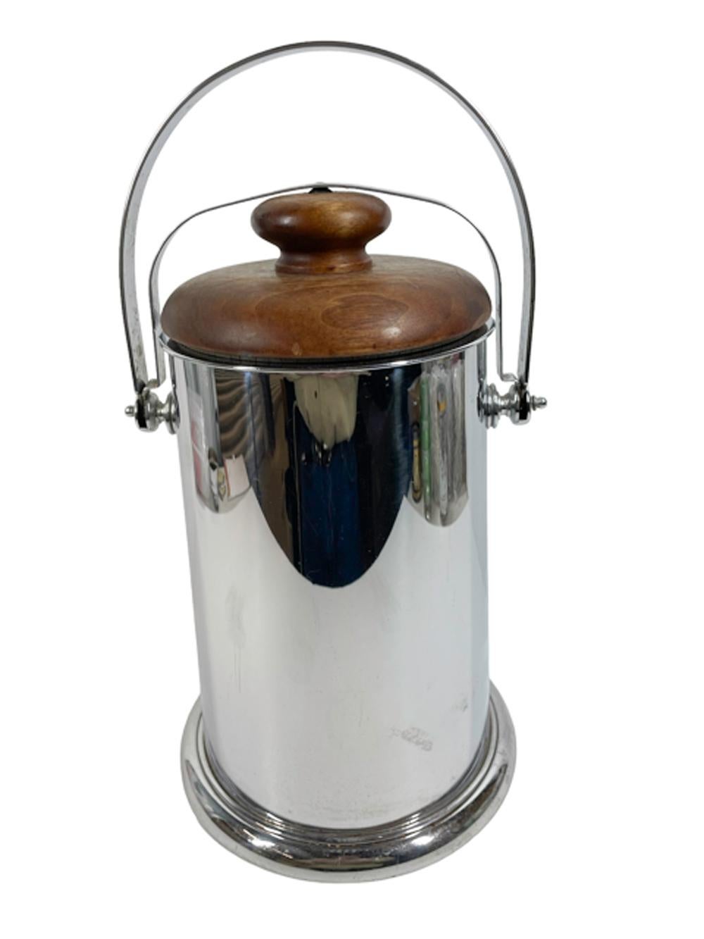 Large, tapered chrome ice bucket by Manning-Bowman having a turned walnut lid and ceramic lining, fitted with a swing handle and lid-lock.