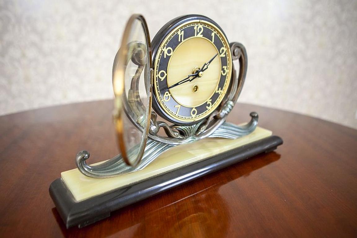 Art Deco Mantel Clock From the Early 20th Century

We present you this Art Deco mantel clock from the early 20th century, made of metal and stone. The dial is covered with a glass and held on both sides by stylized supports. All is placed on a