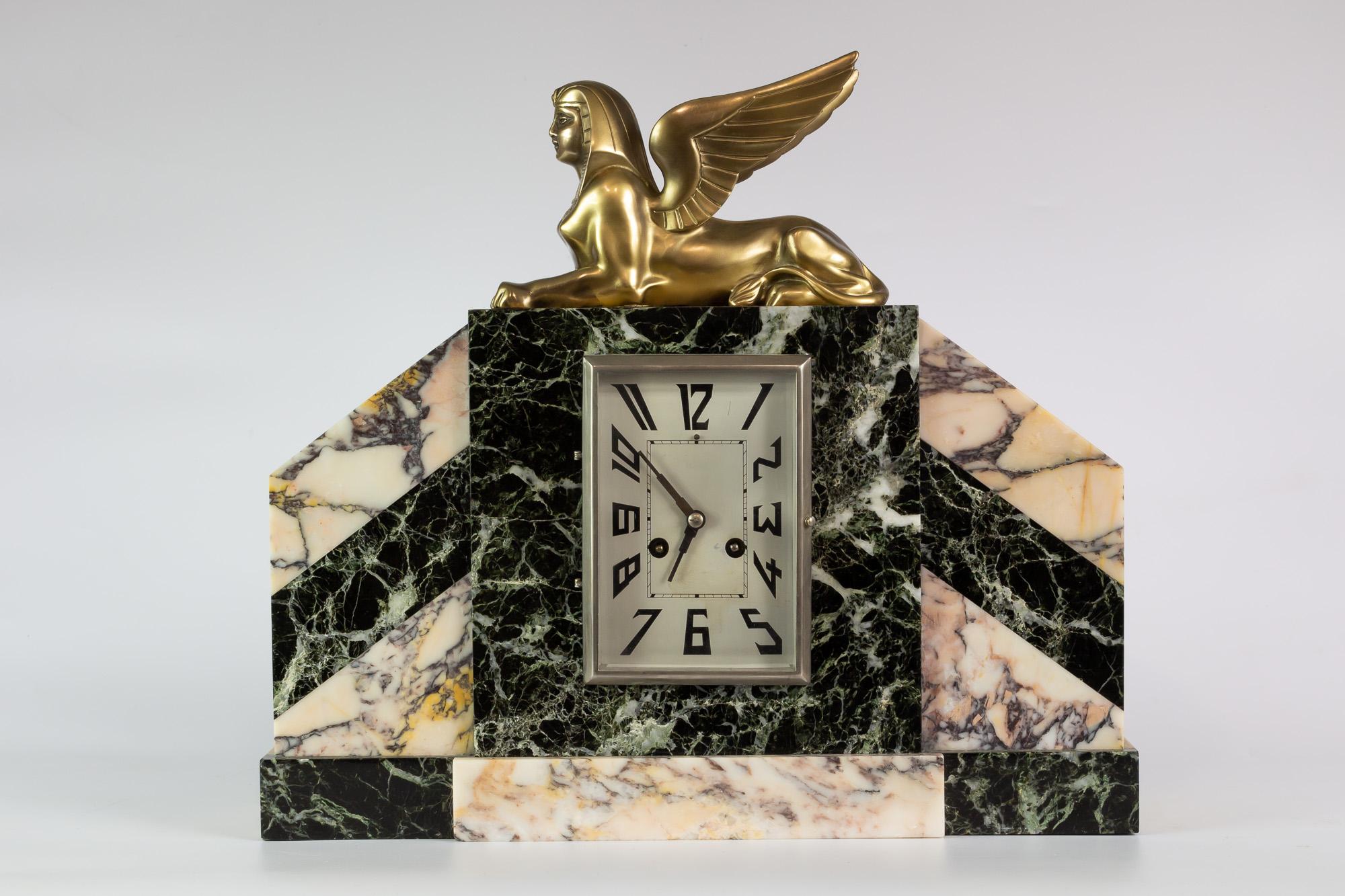 Art deco mantel clock, skyscraper style with garnitures and gilt bronze sphinx.
It is made of marble plates in various shades. Paris Machinery.

Specially good conditions and marble has some typical small cracks due to age. 
The clock works,