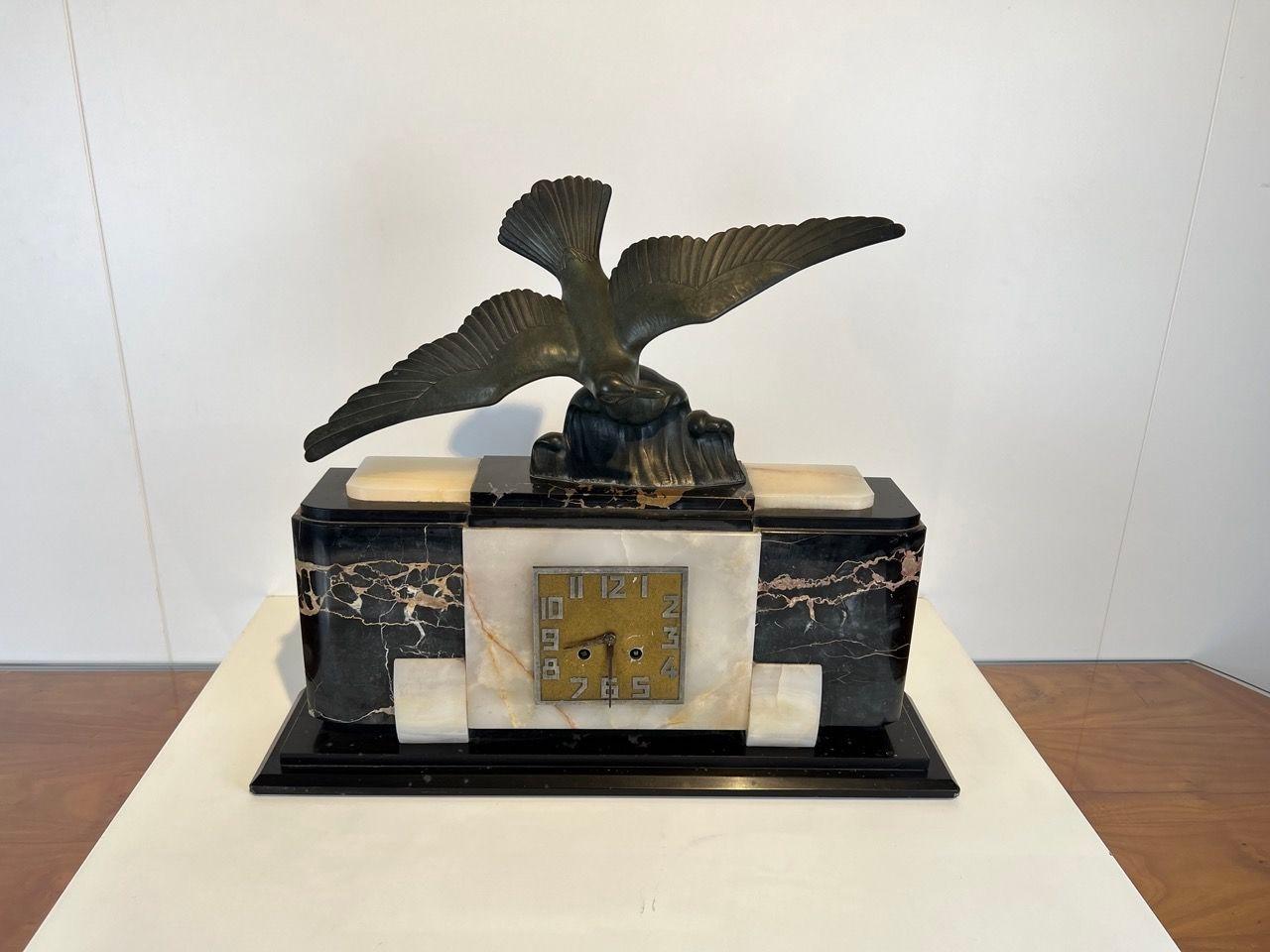 Original, well-preserved Art Deco mantel or table clock from France around 1930.
Marble base in dark (Porto) and light marble. At the top a spelter cast of an albatross bird sculpture with outstretched wings.
Brass dial and original brass winding