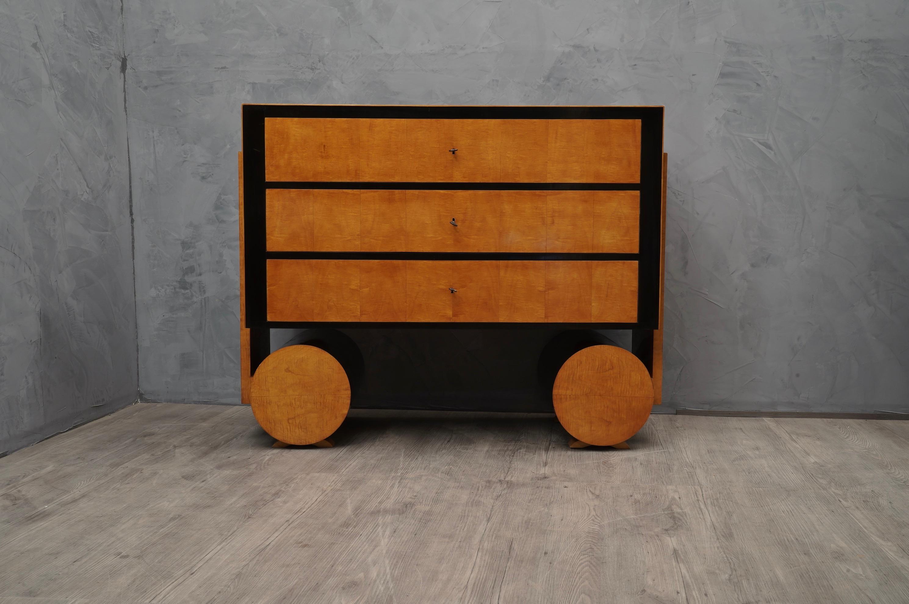 Beautiful dresser from the design very rational but very impact.

All veneered in maple wood, with parts polished in black shellac. Two beautiful round legs support three large drawers. It is very nice the combination of the lacquered black part and