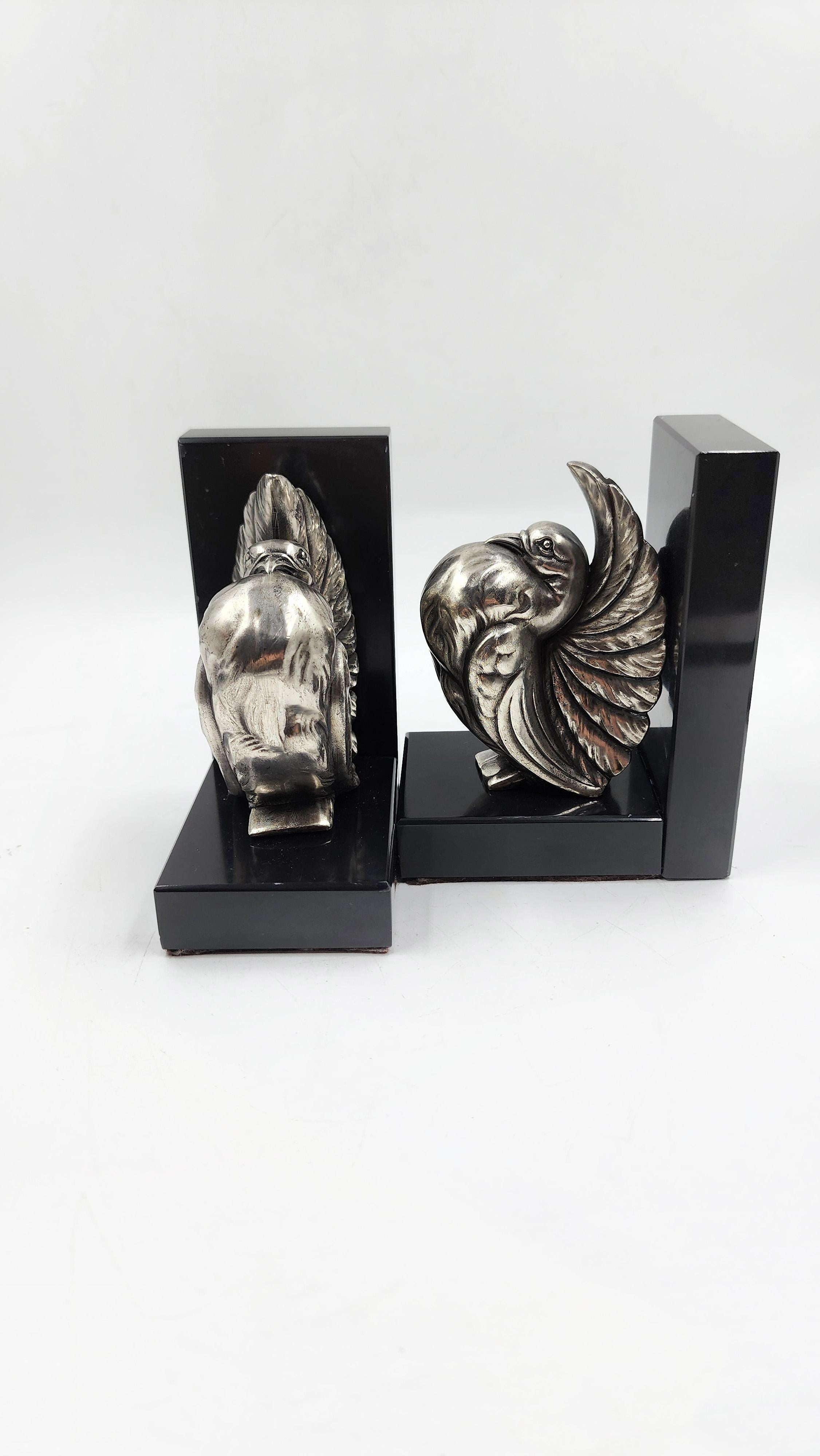 Reggilibri Art Deco francese in marmo e bronzo con colomba
Coppia di reggilibri in stile Art Déco francese, realizzati in marmo nero lucido e bronzo argentato. Ogni pezzo presenta una base rettangolare in marmo che si estende verticalmente per