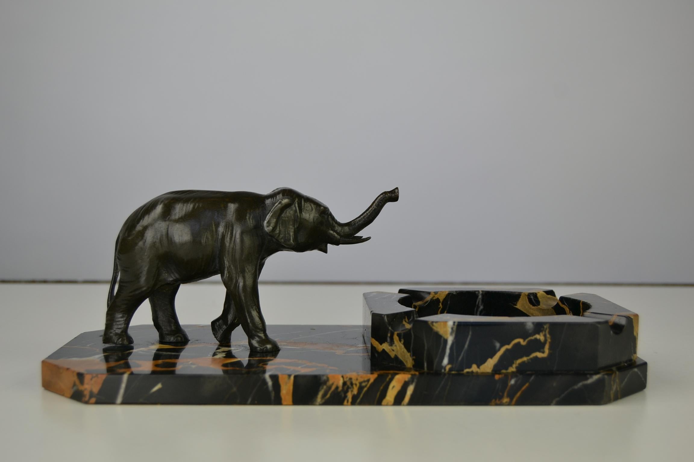 Art Deco marble ashtray on a marble base with an elephant figurine.
An Art Deco figural ashtray or Art Deco desk accessory. 
The Italian marble - Portoro marble - has the stylish colors black with gold and brown veins. The elephant figurine is