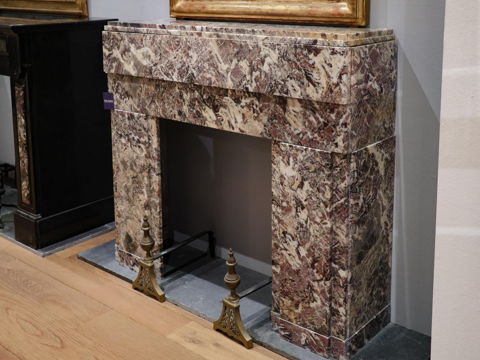 Cette étonnante cheminée Art déco, fabriquée dans les années 1920, présente un mélange captivant de teintes de marbre rose, jaune, gris et blanc. La pièce est en excellent état et témoigne de l'élégance intemporelle et du style distinctif de