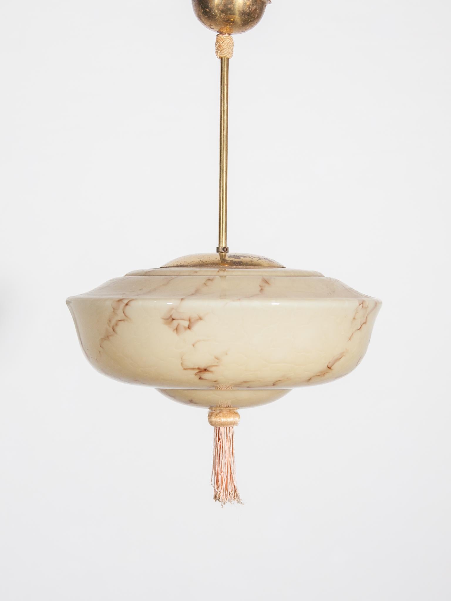 Originale lampada a sospensione Art Déco con paralume in vetro opalino con motivo a marmo ed elementi in ottone che emettono una splendida luce soffusa. Tipica lampada a sospensione da utilizzare in soggiorno, in camera da letto o in corridoio. La