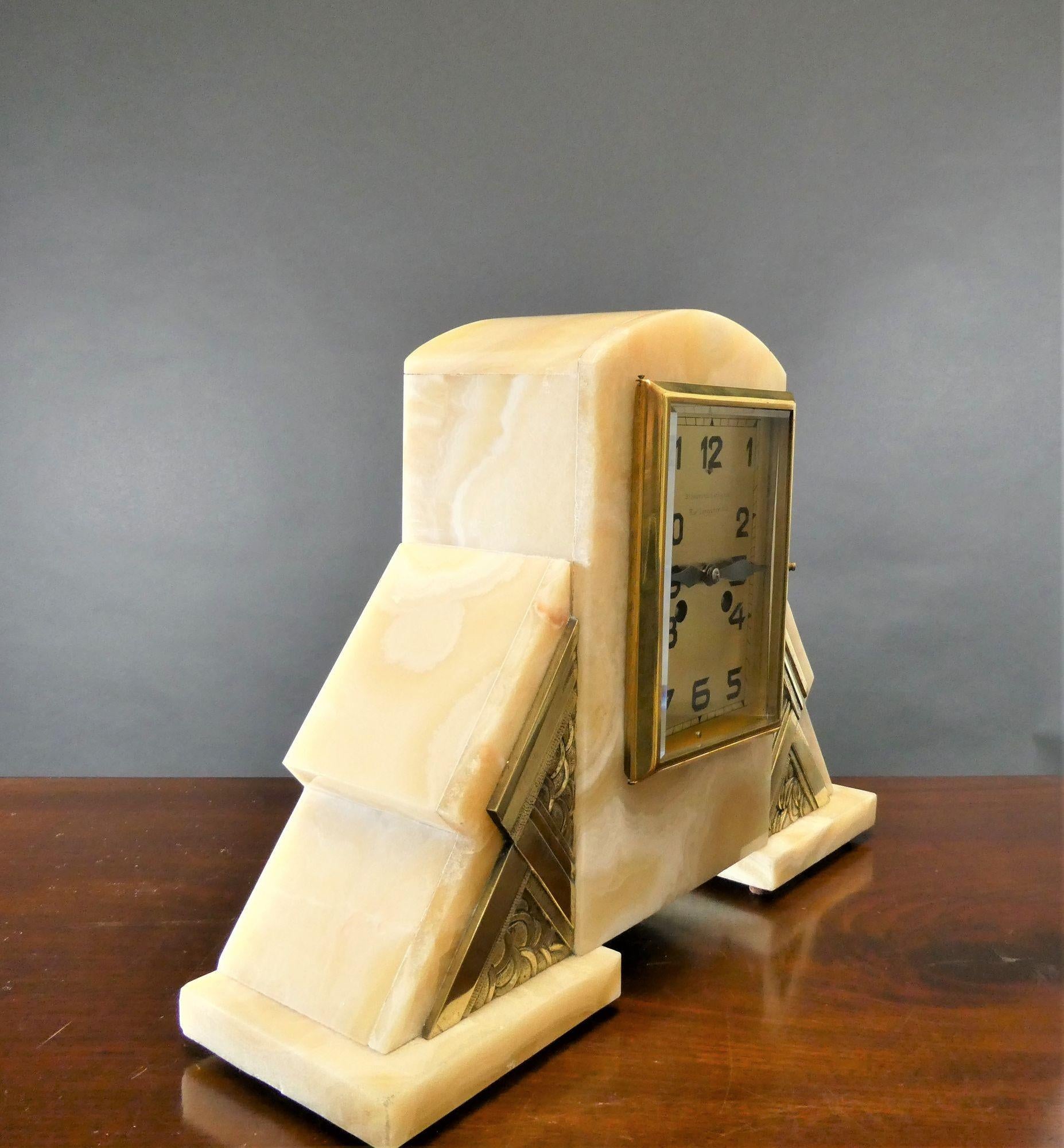 Art Deco Mantel Clock
 
 
 
Art Deco mantel clock house in a finely figured marble stepped case with applied Art Deco style brass mounts.
 
Rectangular brass bezel opening to the gilded dial with Art Deco style numerals and hands signed