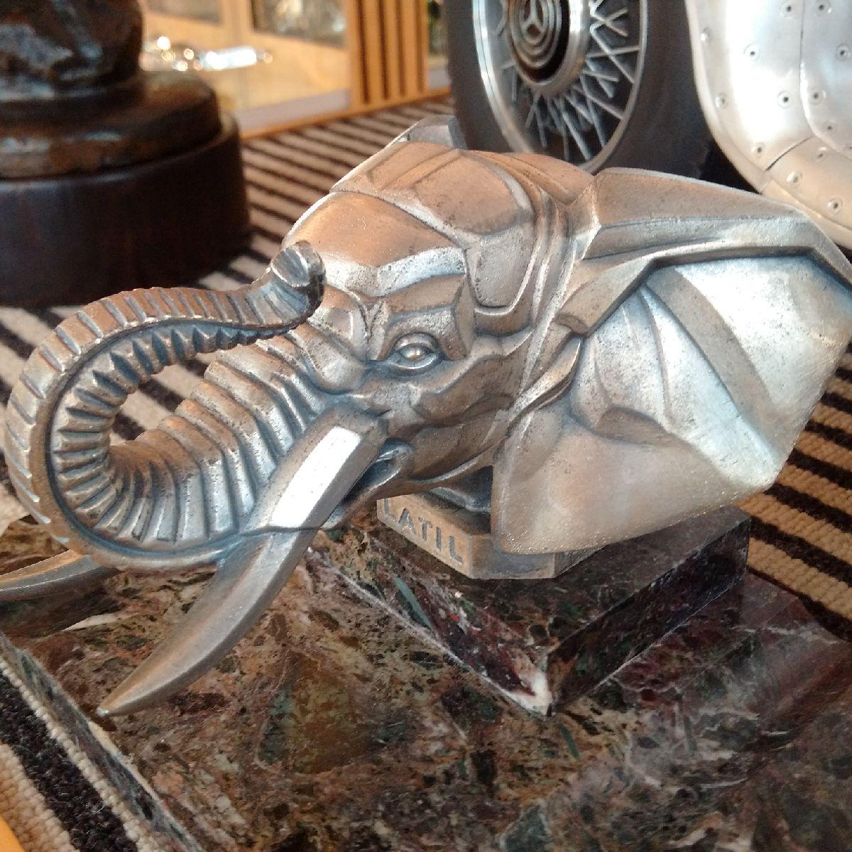 François Bazin (French, 1897-1956)

‘The Latil Elephant’. 

A very striking Art Deco marble pen tray featuring to the centre a polished heavy cast car mascot in the form of an elephant, with trunk held aloft. The mascot’s octagonal plinth has a