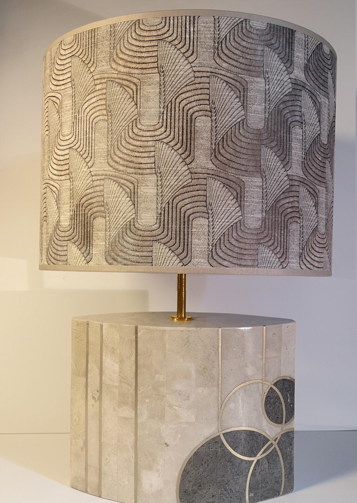 Une lampe de table unique avec une grande base en marbre. La lampe est ornée de cercles et de détails en or. Il est livré avec un abat-jour fait à la main avec un motif rayé qui donne une lumière chaude.
La lampe est fabriquée en Italie, en Europe,