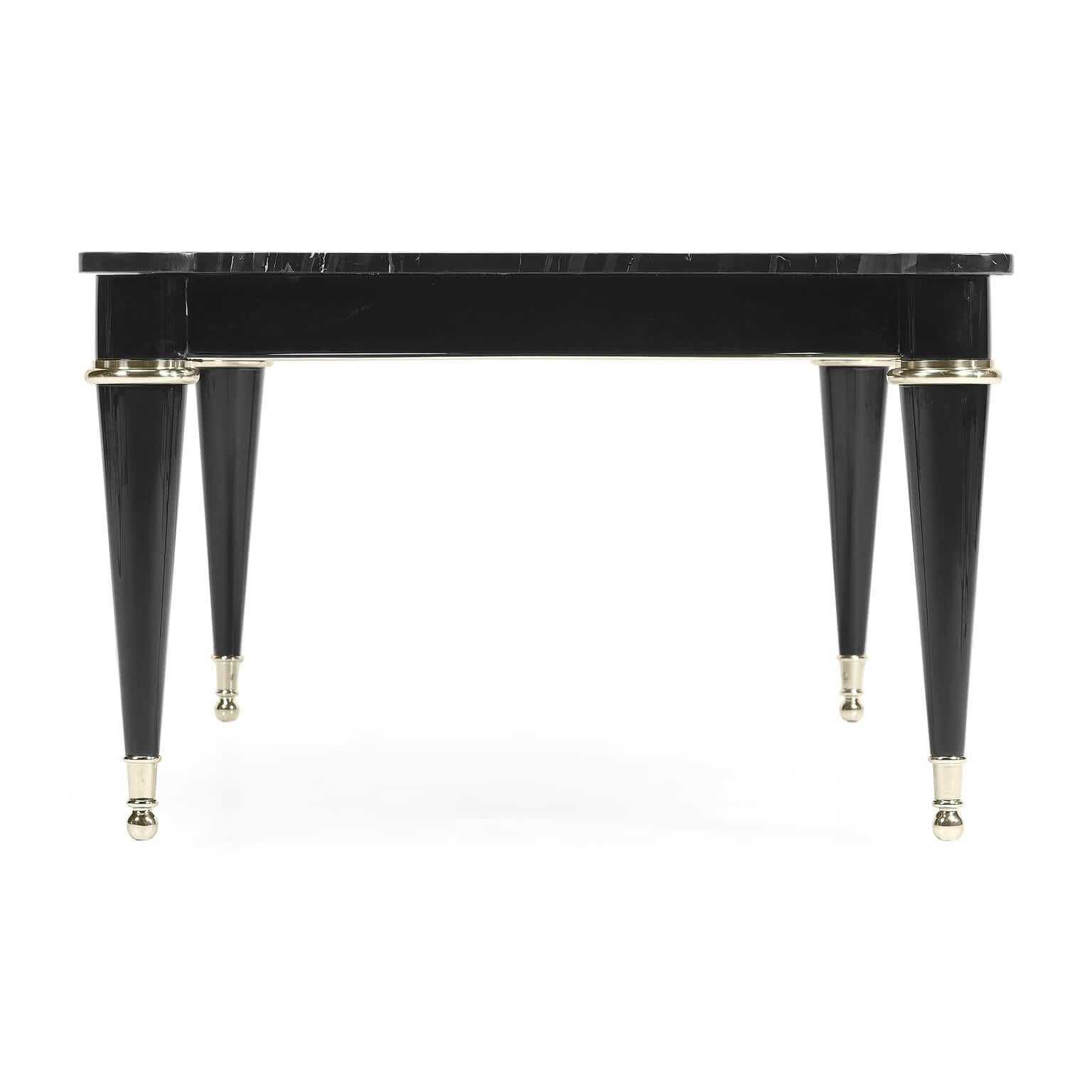 An Art Deco inspired black marble top cocktail table with silvered details, cookie-cut corners, and raised on a painted piano black base with turned and tapered legs.

Dimensions: 54